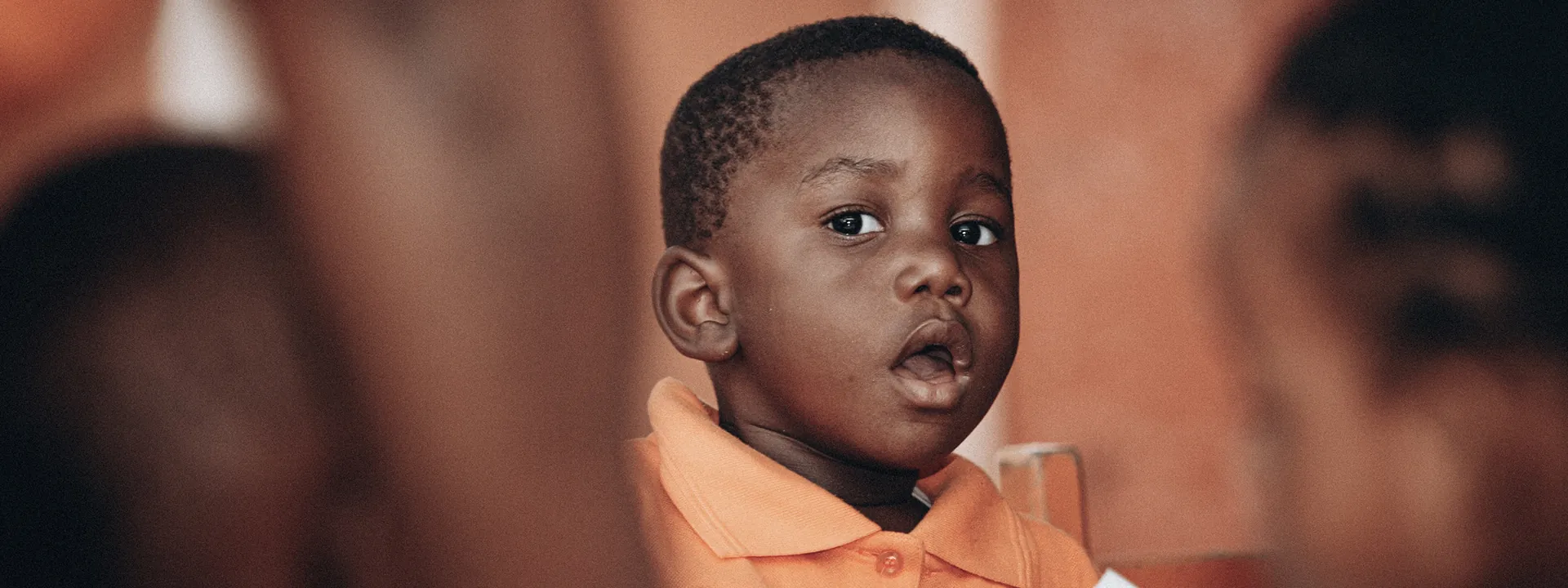 Young child in orange clothing looking to the side