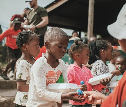 Children receiving food and supplies from Karuna community aid volunteers