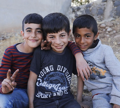 Three smiling boys embracing outdoors, reunited with family in Ukraine