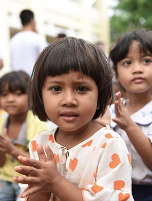 Smiling young girl clapping with children in the background, encouraging supporters to start a fundraiser