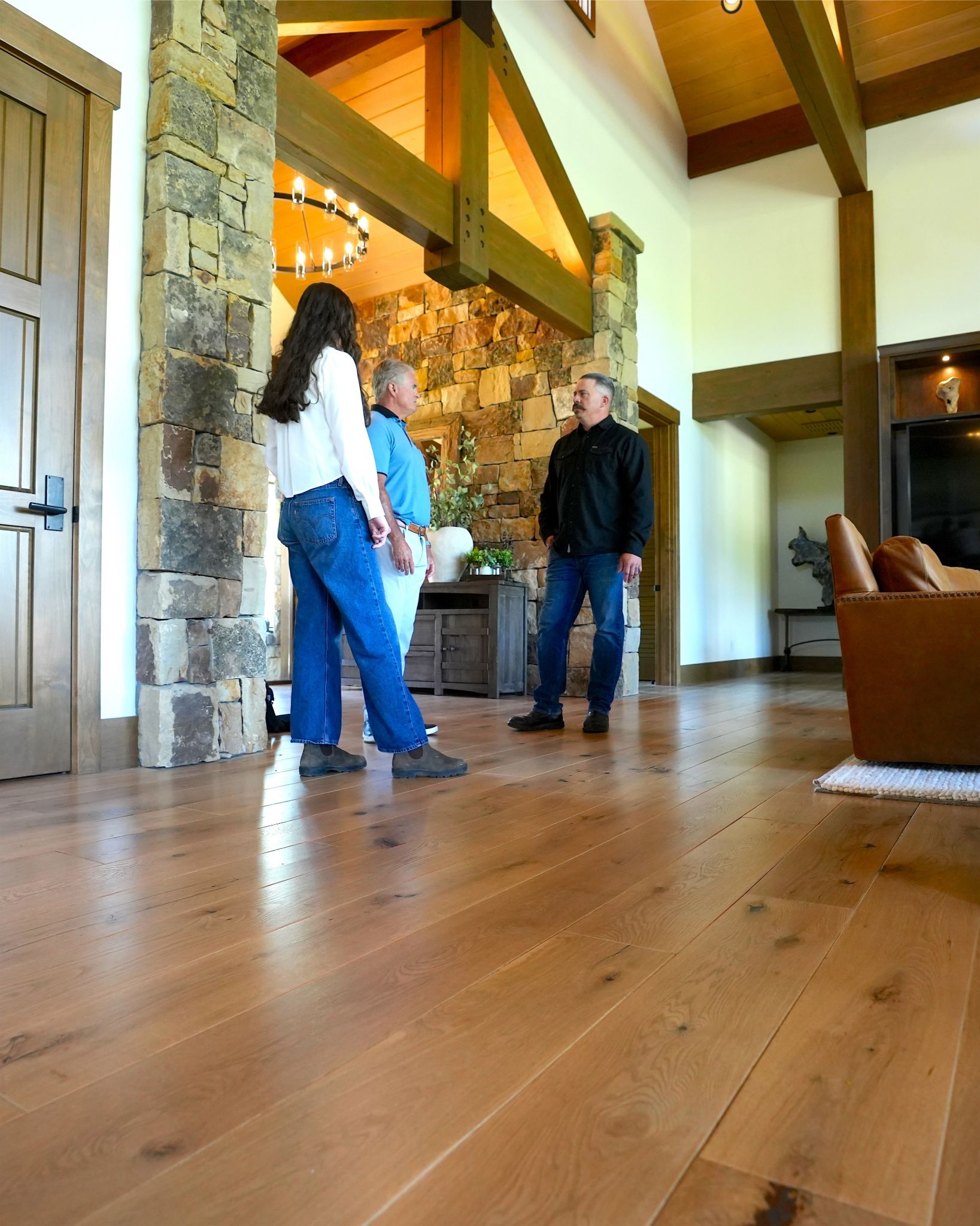 Bright room with large hardwood floor, kitchen area, stone wall, and glass sliding doors.