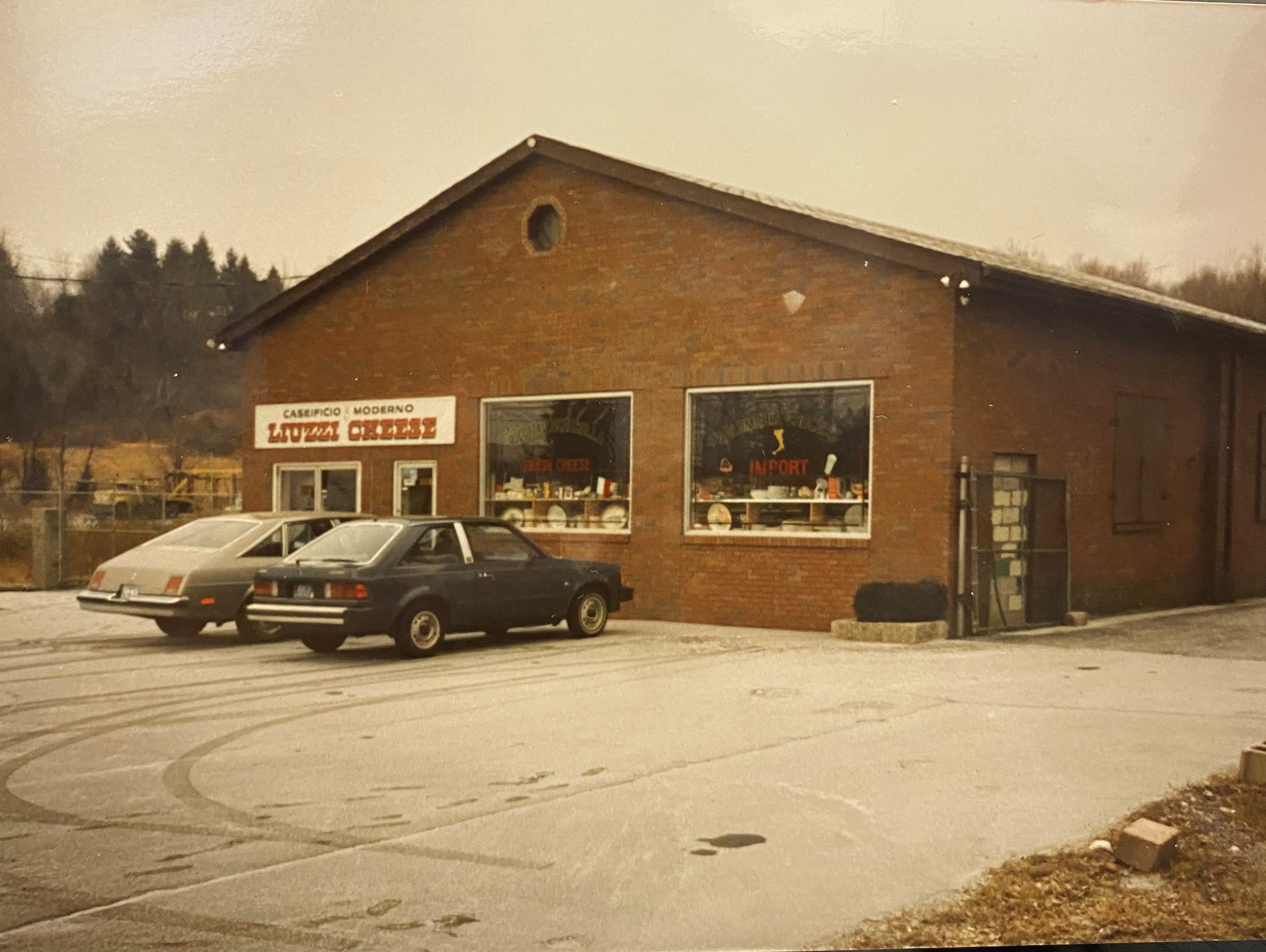The original Liuzzi Cheese with two parked cars in front and a sign reading 'Liuzzi Cheese' above the entrance in 1981.