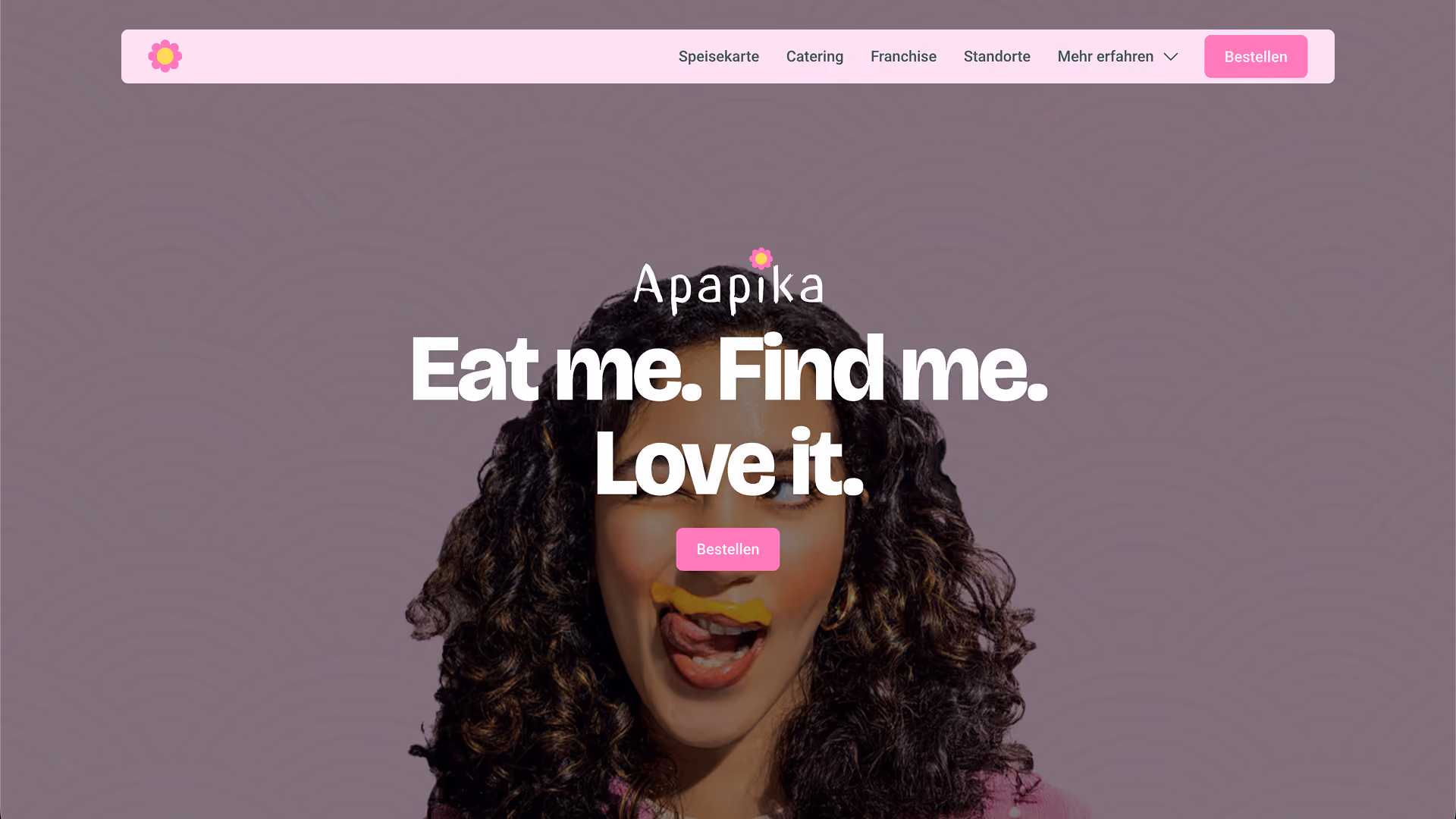 Apapika-Startseite mit einer lächelnden Frau, umrahmt von lockigem Haar, dem markanten Schriftzug „Eat me. Find me. Love it.“ und einer verspielten, pinkfarbenen Navigation.