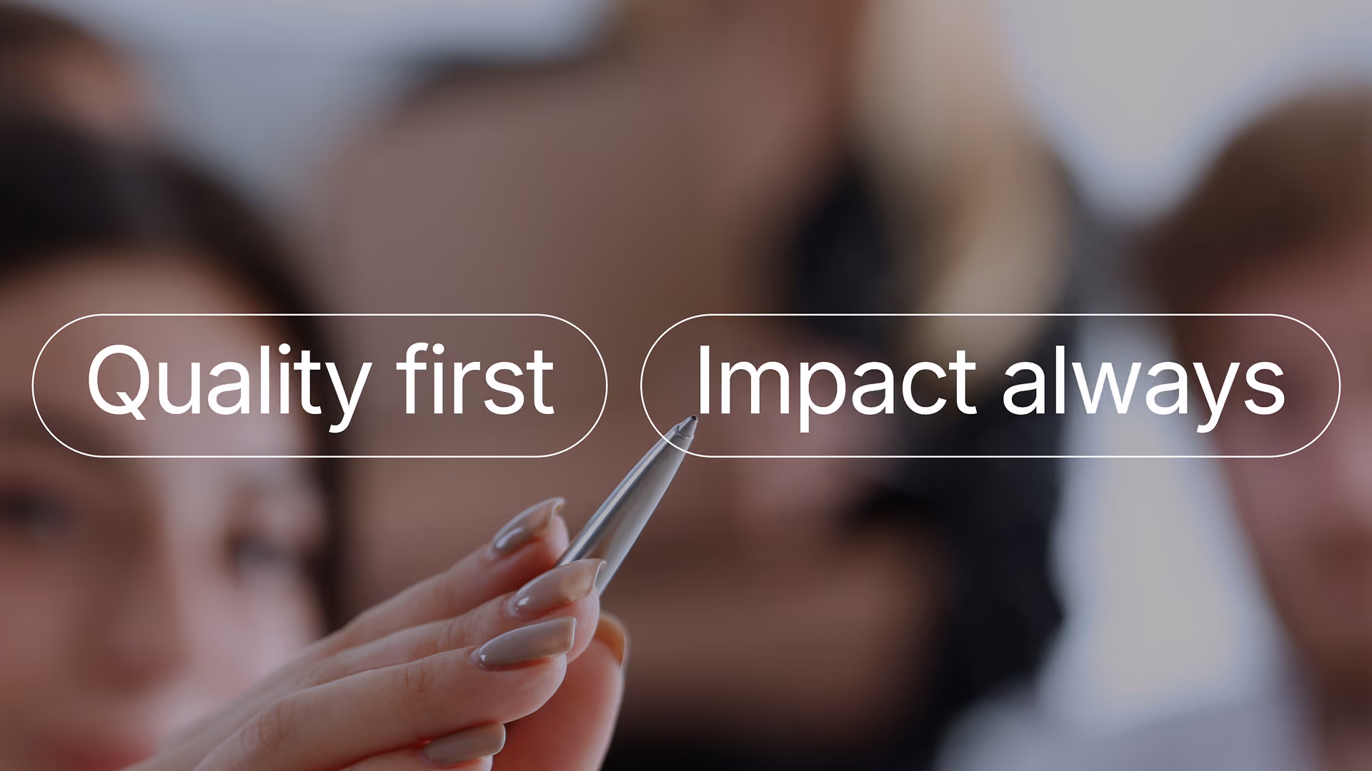 Ein unscharf dargestelltes Team im Gespräch, im Vordergrund eine Hand, die einen Eingabestift hält; die Texteinblendungen „Quality first“ und „Impact always“ vermitteln den Fokus.