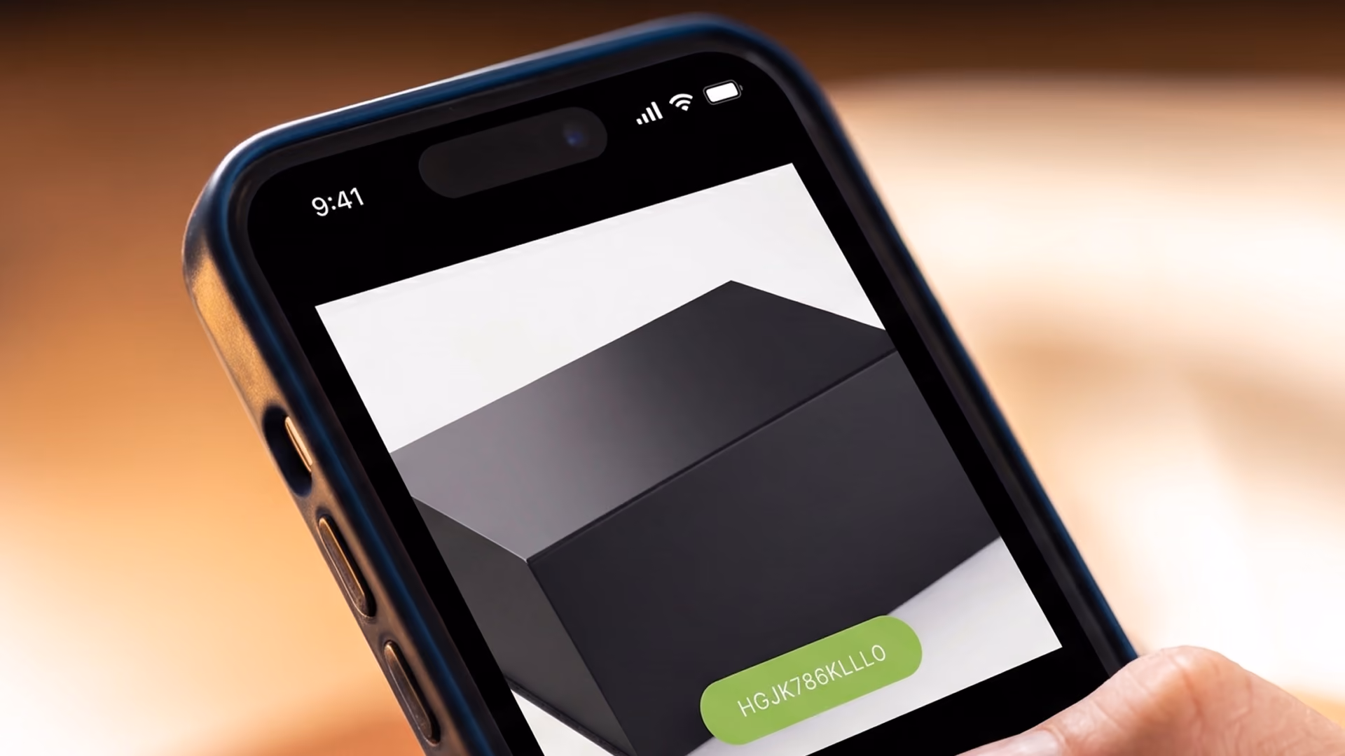 Ein schräg liegendes Smartphone auf einer warmen, unscharfen Oberfläche zeigt in einer App ein minimalistisches, schwarzes, geometrisches Kästchen mit einem hellgrünen Button darunter.