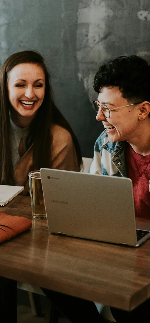 Duas jovens conversando e utilizando o computador