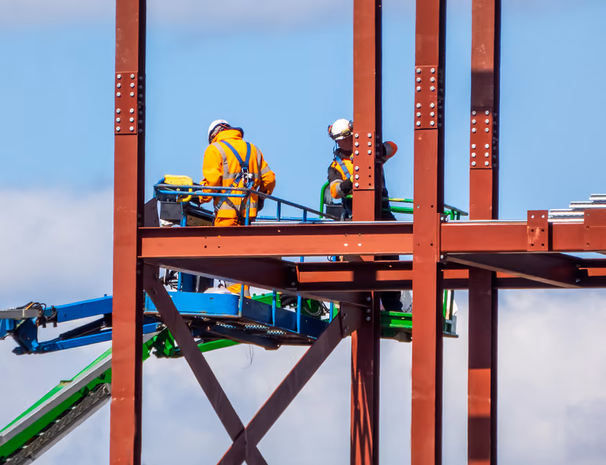 Ironworker assembling structural steel beams at a construction site in Riverside.