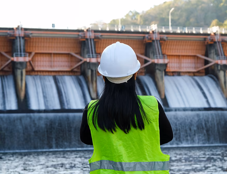 Hydroelectric plant technician checking operational systems of a dam at a renewable energy plant.