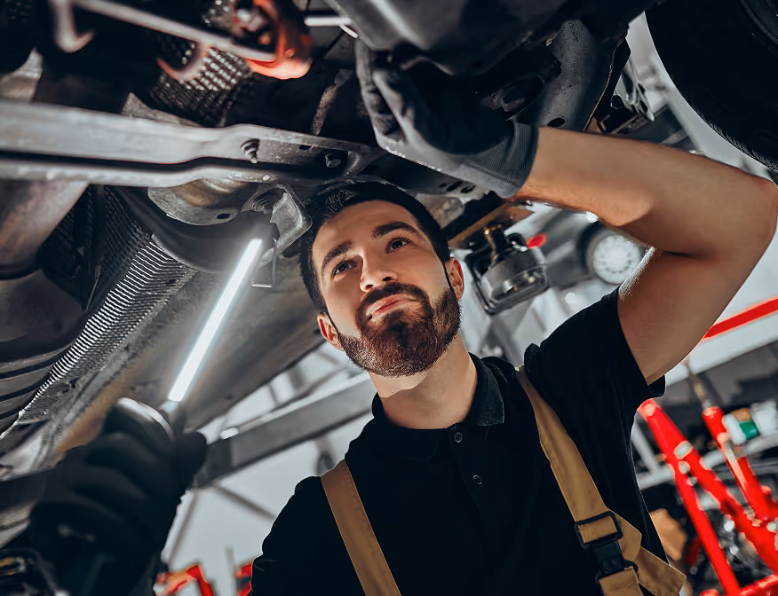 Man repairing a car as part of an auto mechanic apprenticeship job.