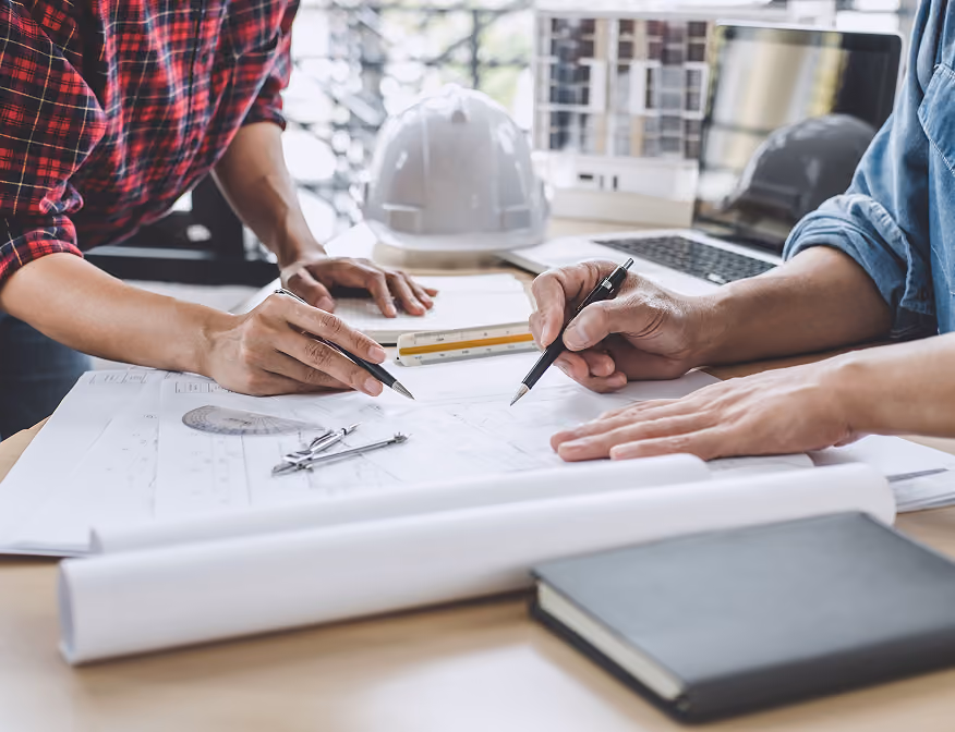 Two civil engineers reviewing blueprints for a sustainable building construction project.
