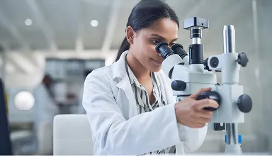 A researcher in a lab looking through a microscope