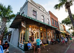 Busy crowds around shopfronts and tropical trees