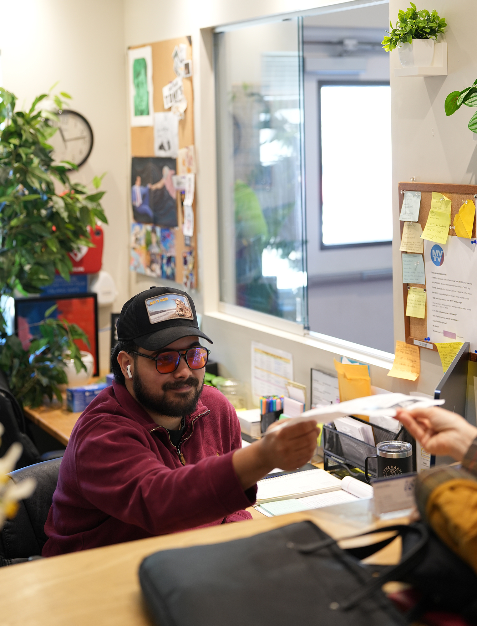 Anthony Vilaca, Programming & Facilities Coordinator, hands paperwork to a MVTV member visiting the studio