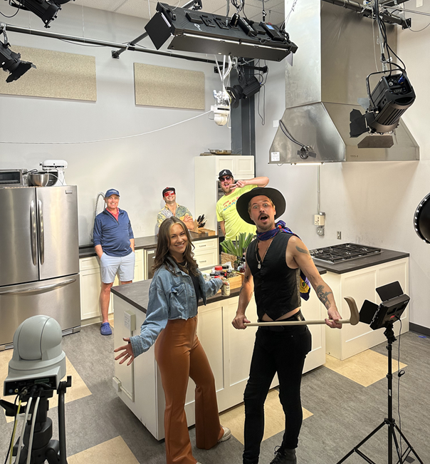 An excited crew smiles for the camera in the MVTV kitchen studio