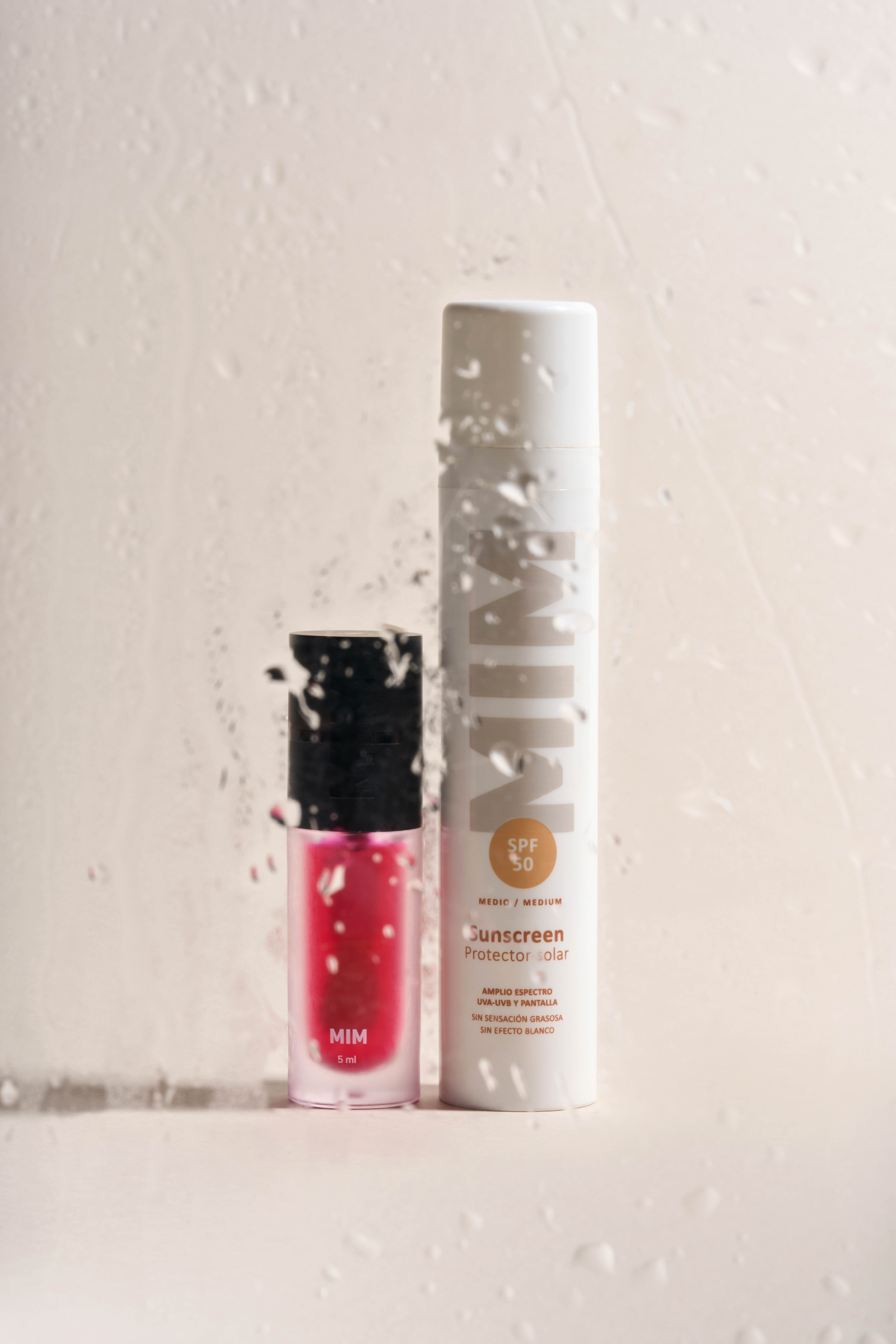 Creative product photography by Gooper: MIM sunscreen and liquid lip tint styled with a water drops and paint-splatter effect on beige.