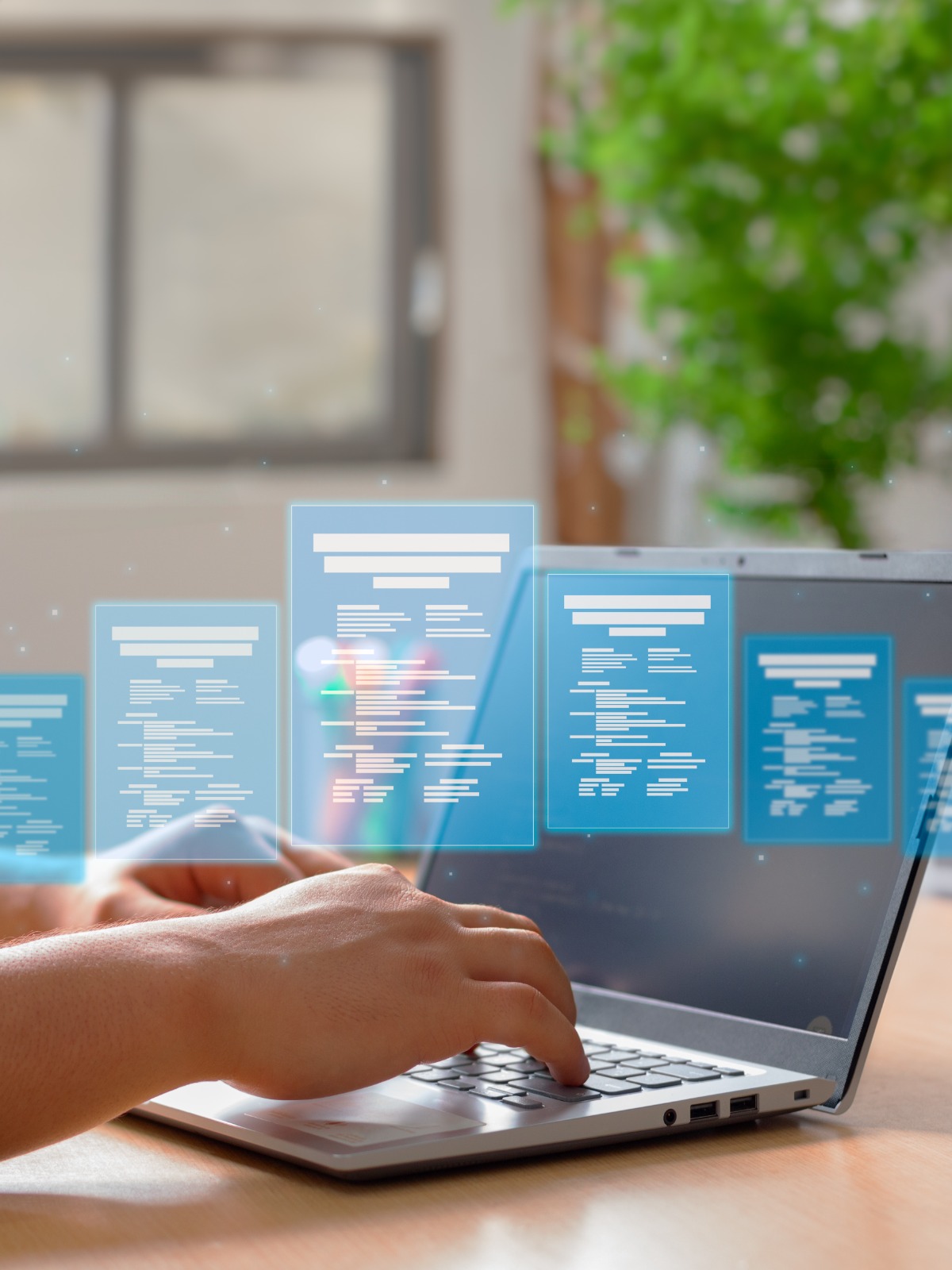 Hands typing on a laptop keyboard with floating digital documents above the laptop.