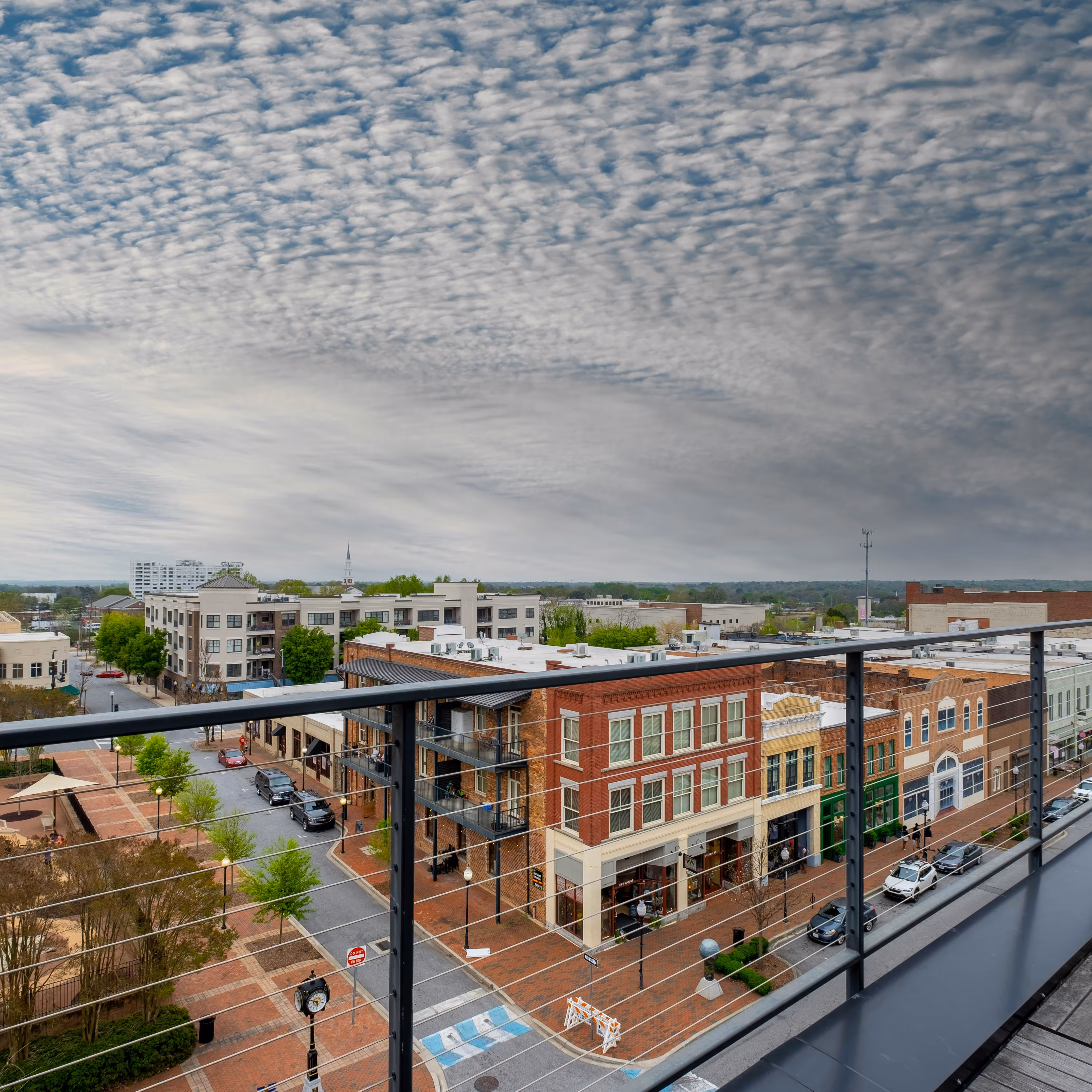 Elevated view of a downtown area in Spartanburg, South carolina with brick sidewalks, parked cars, historic buildings, and dramatic cloudy sky.