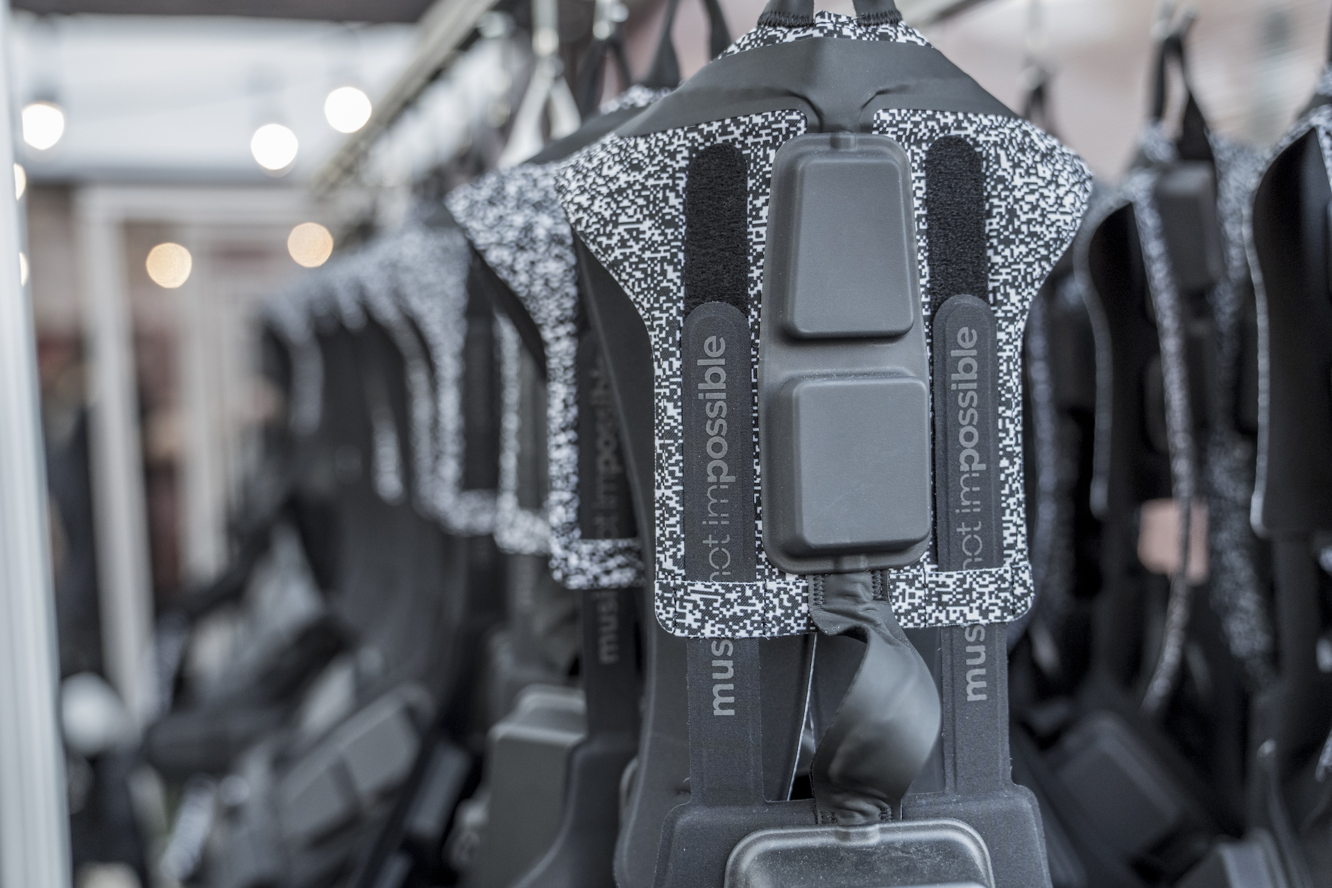 Row of Not Impossible wearable haptic suits hanging on racks, featuring assistive music technology designed for accessibility and sensory feedback.