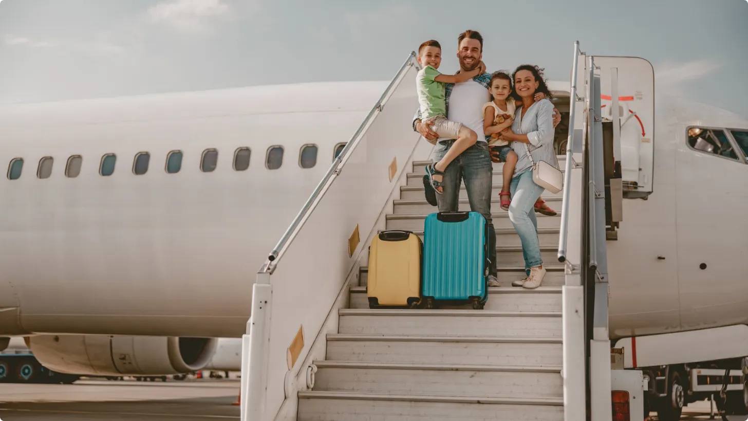 Family with two children and luggage on an airplane boarding staircase