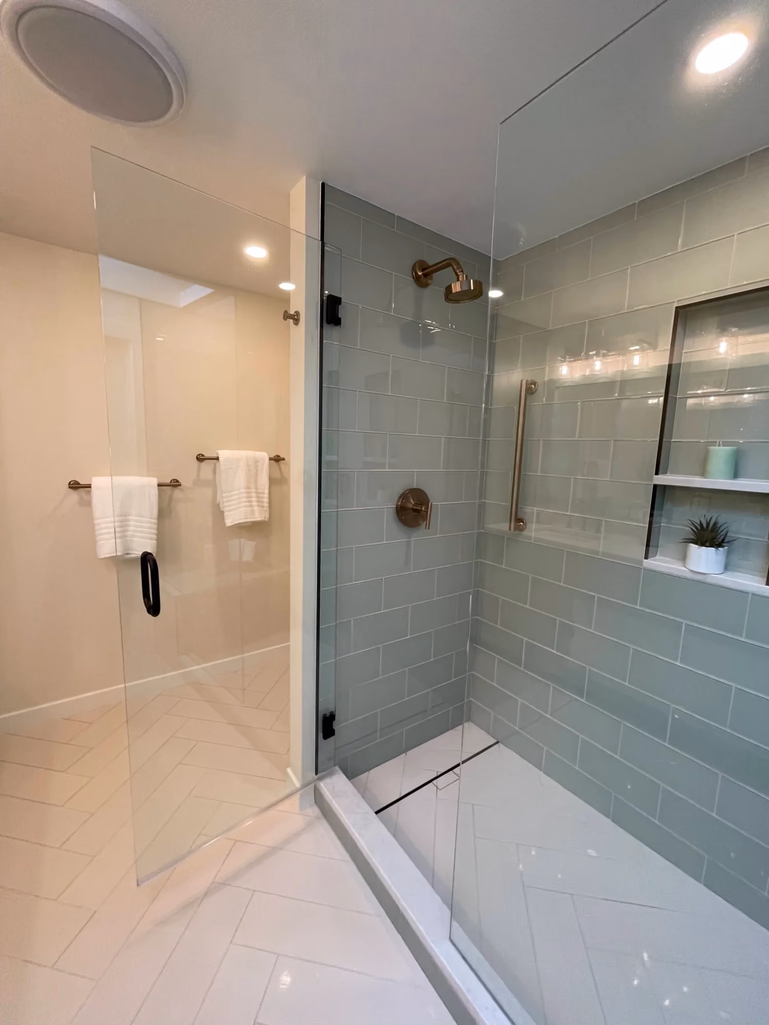 Glass-enclosed shower with tiled walls and built-in bench