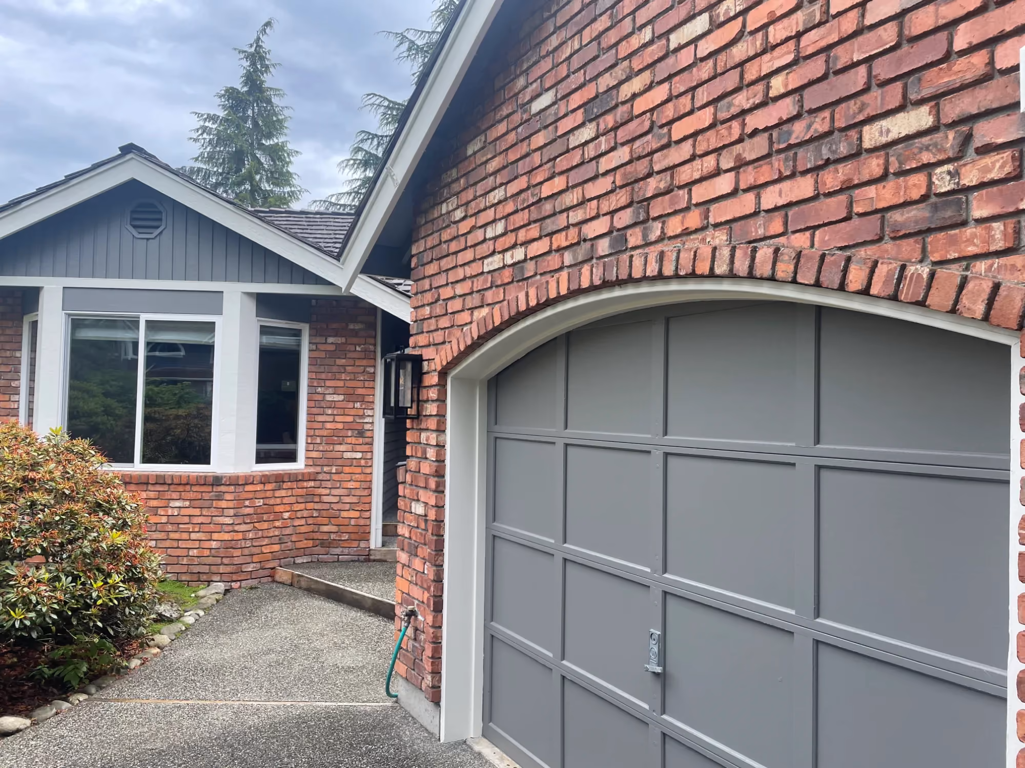 Exterior view of a house with a gray garage door and brick facade