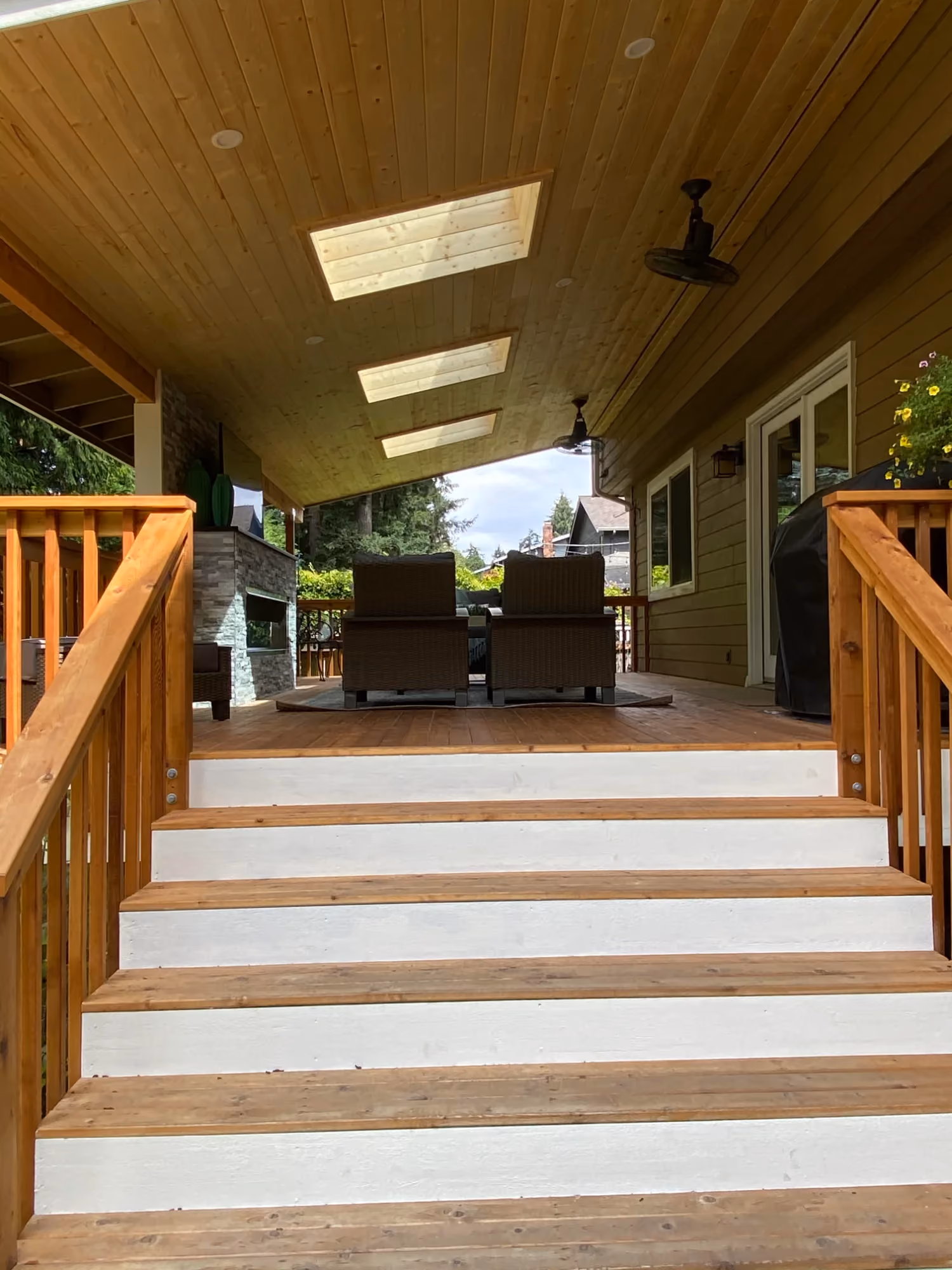 Stairway with wooden railings leading into a covered entry