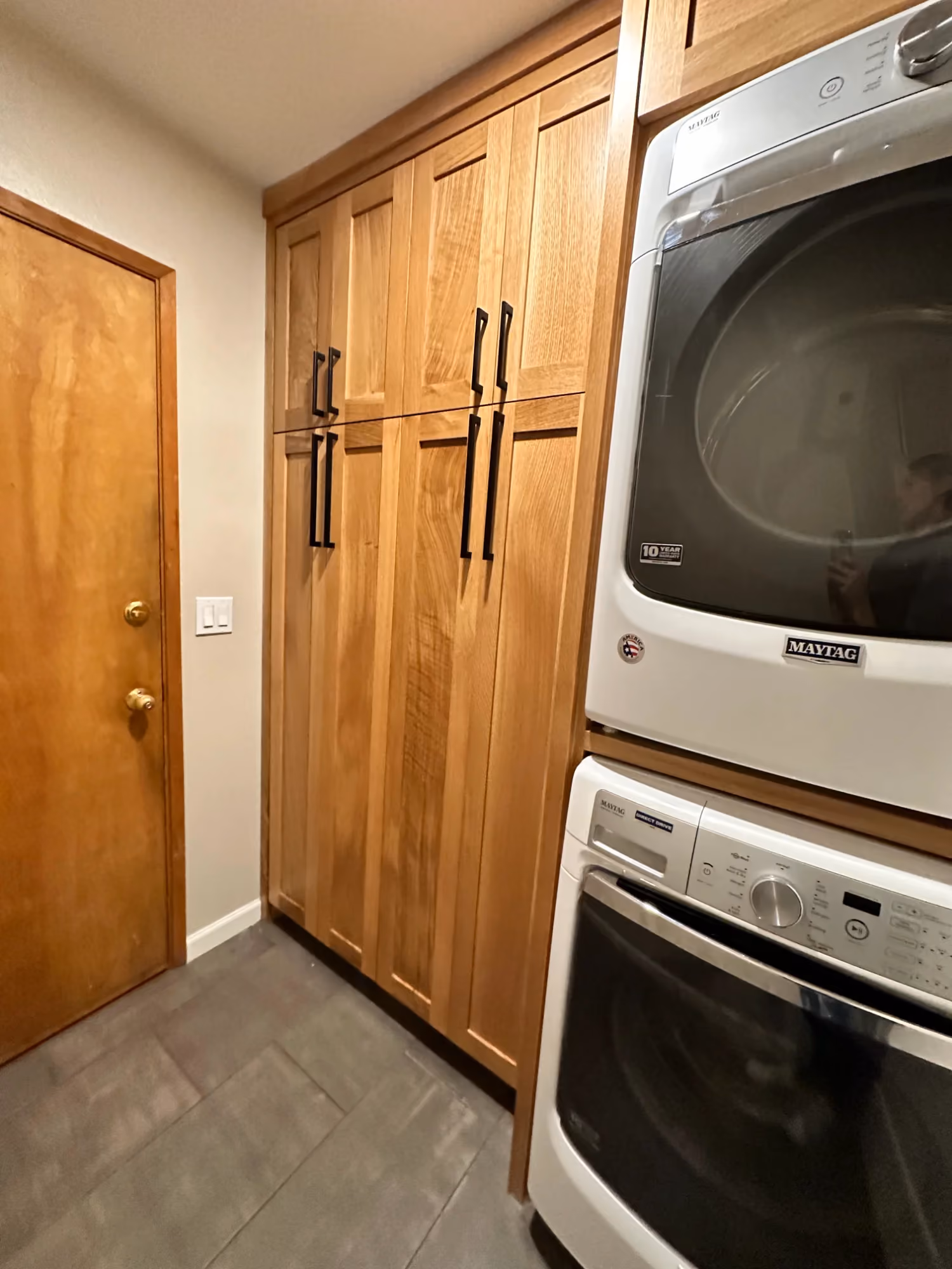 Laundry closet with stacked washer and dryer next to cabinets