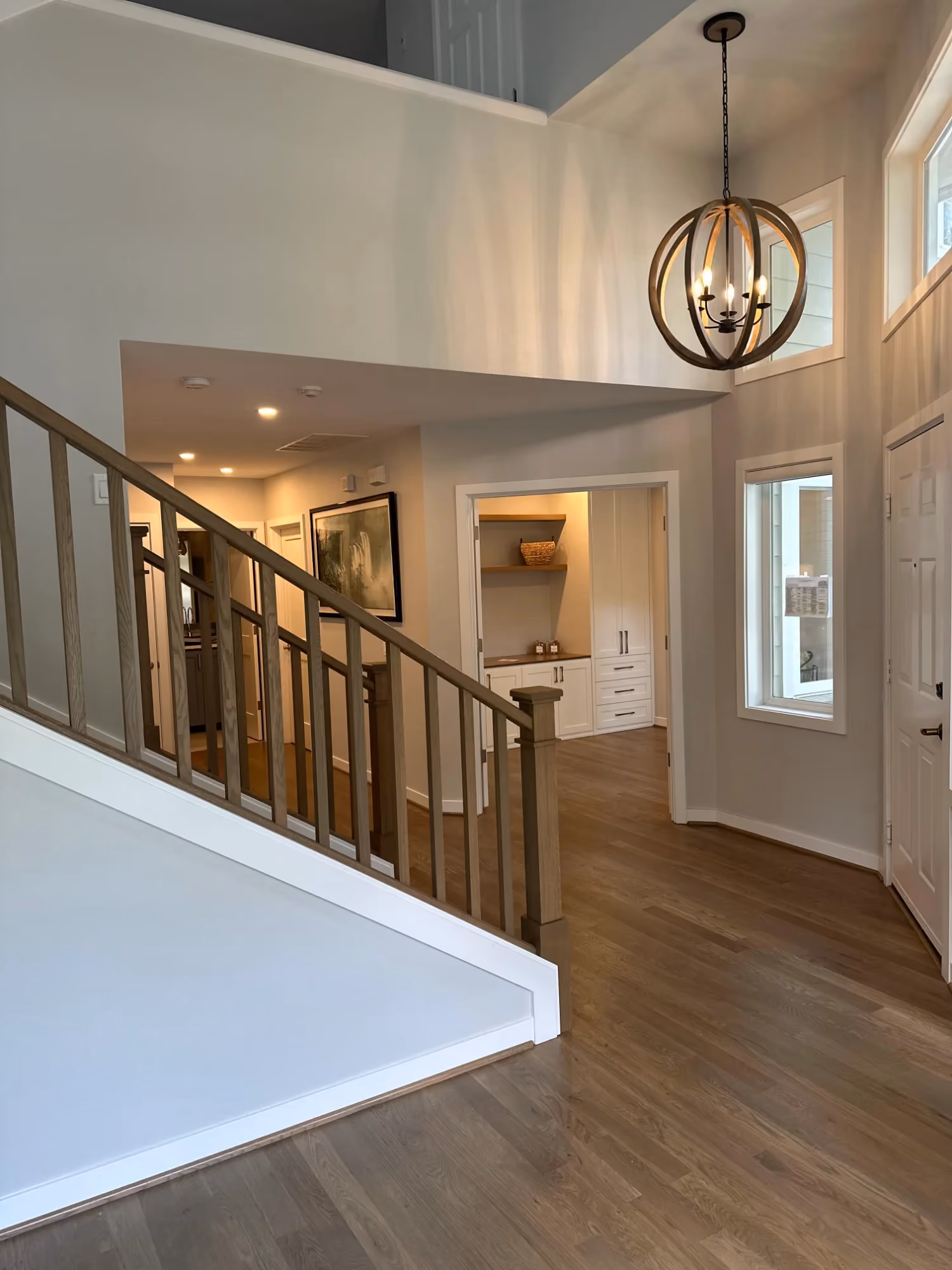Foyer with staircase, pendant light, and wood floors