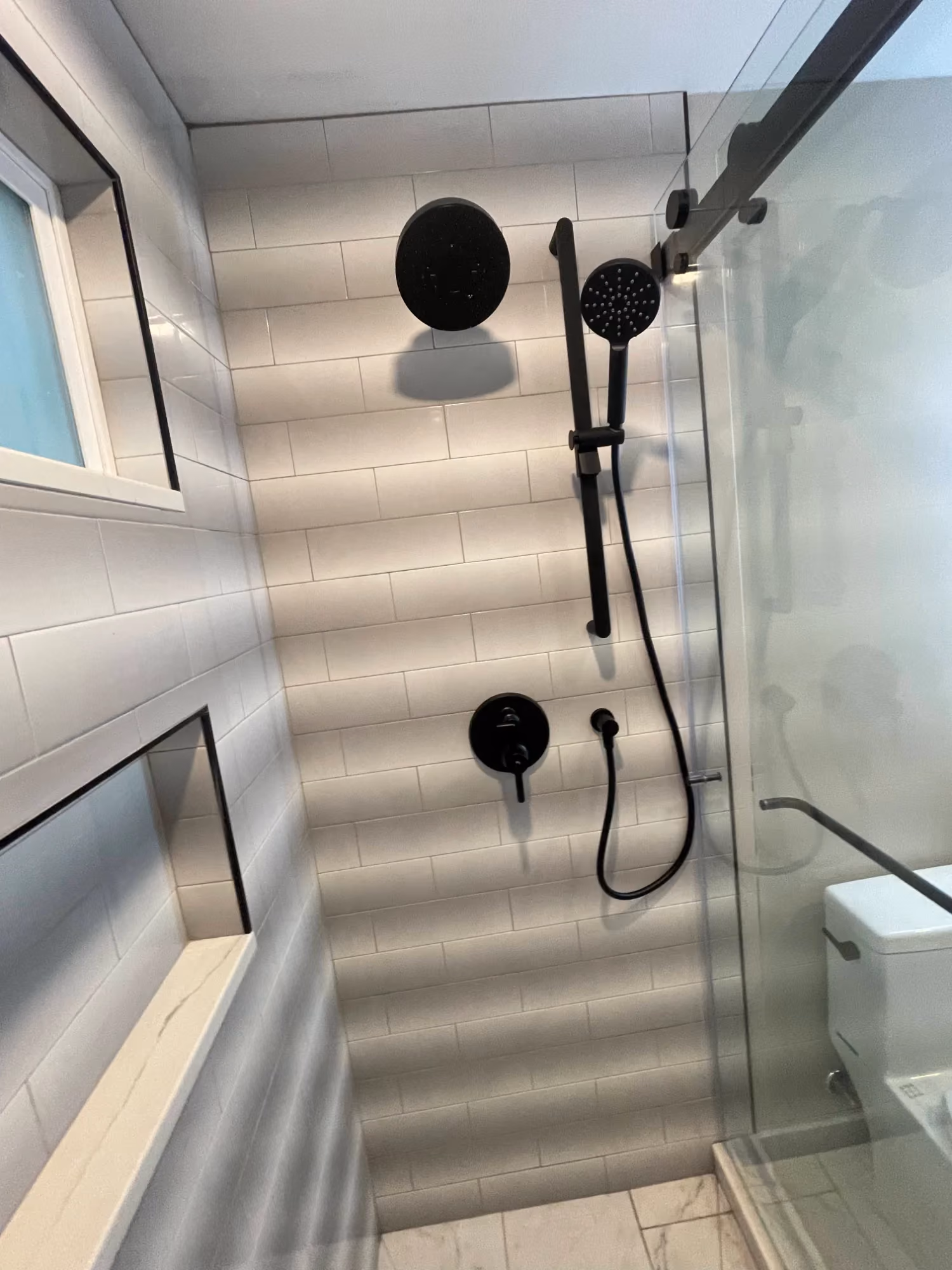 Walk-in shower with glass door and black fixtures