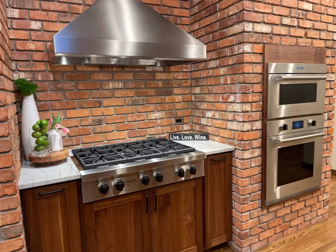 Brick-wall kitchen with gas range and stainless hood
