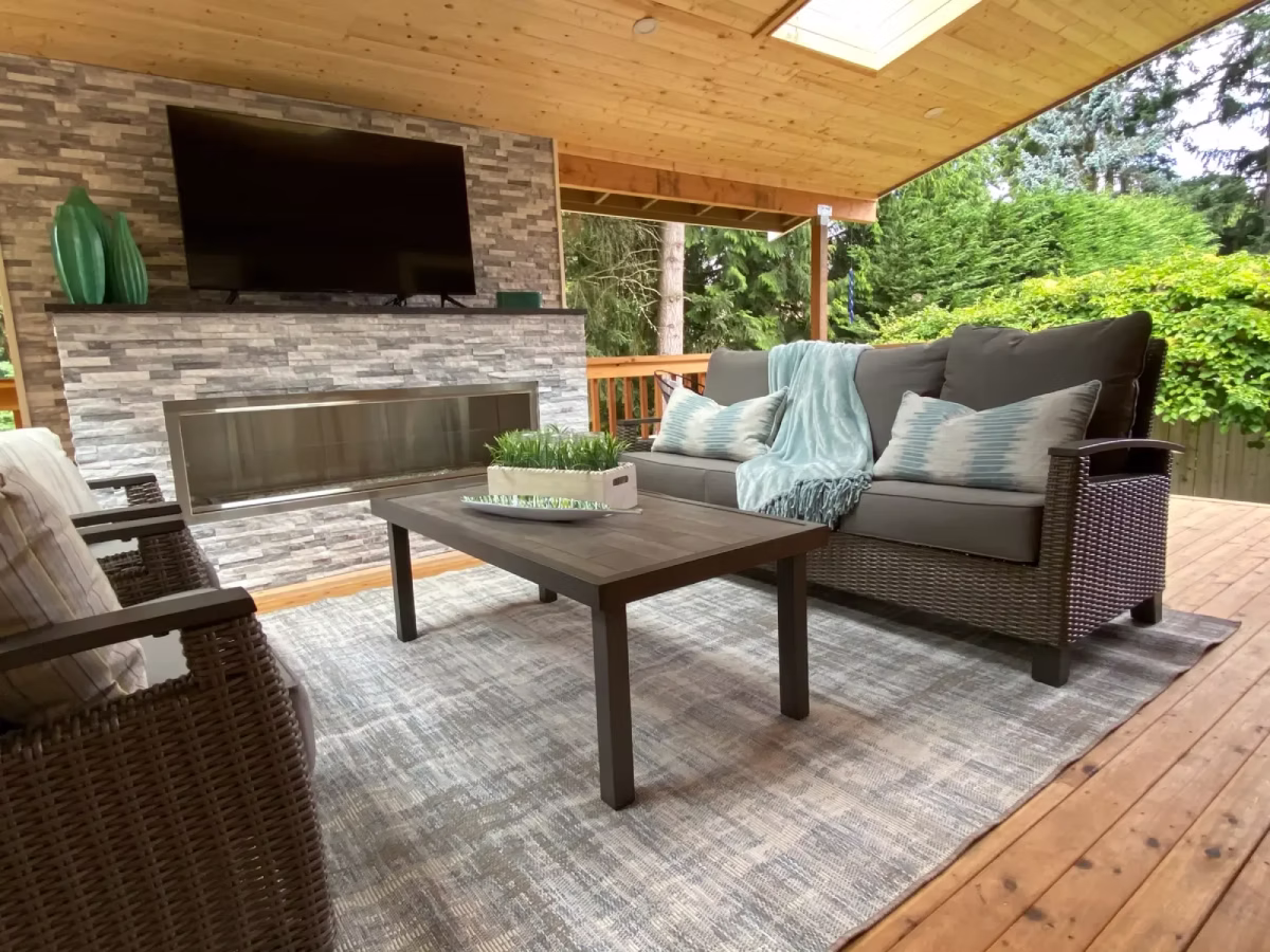 Covered outdoor patio with dining table, chairs, and stone fireplace