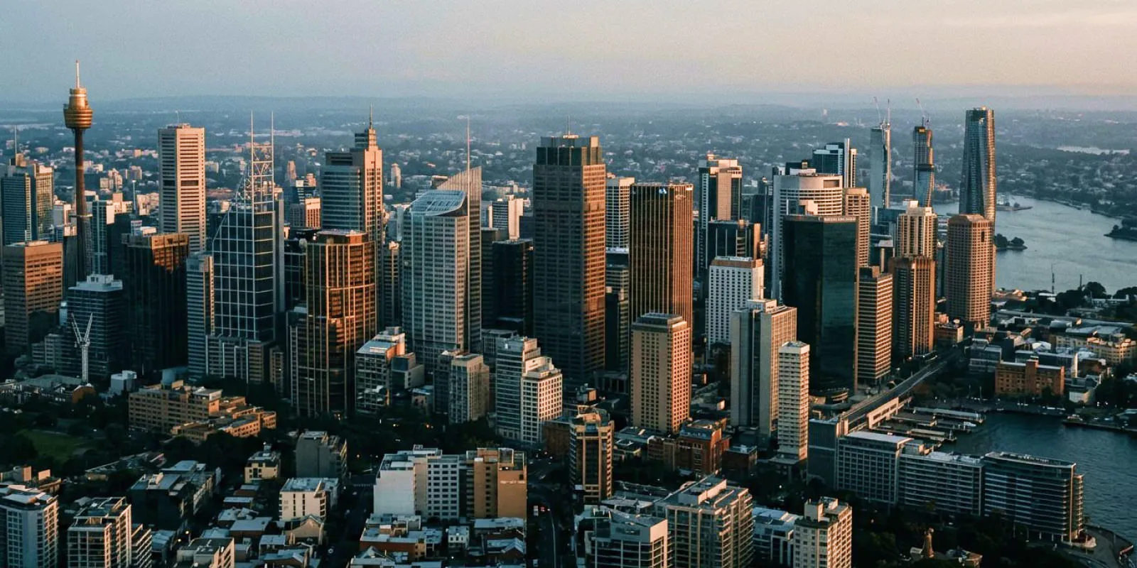 Aerial view of a city skyline with tall skyscrapers and a river at sunset.