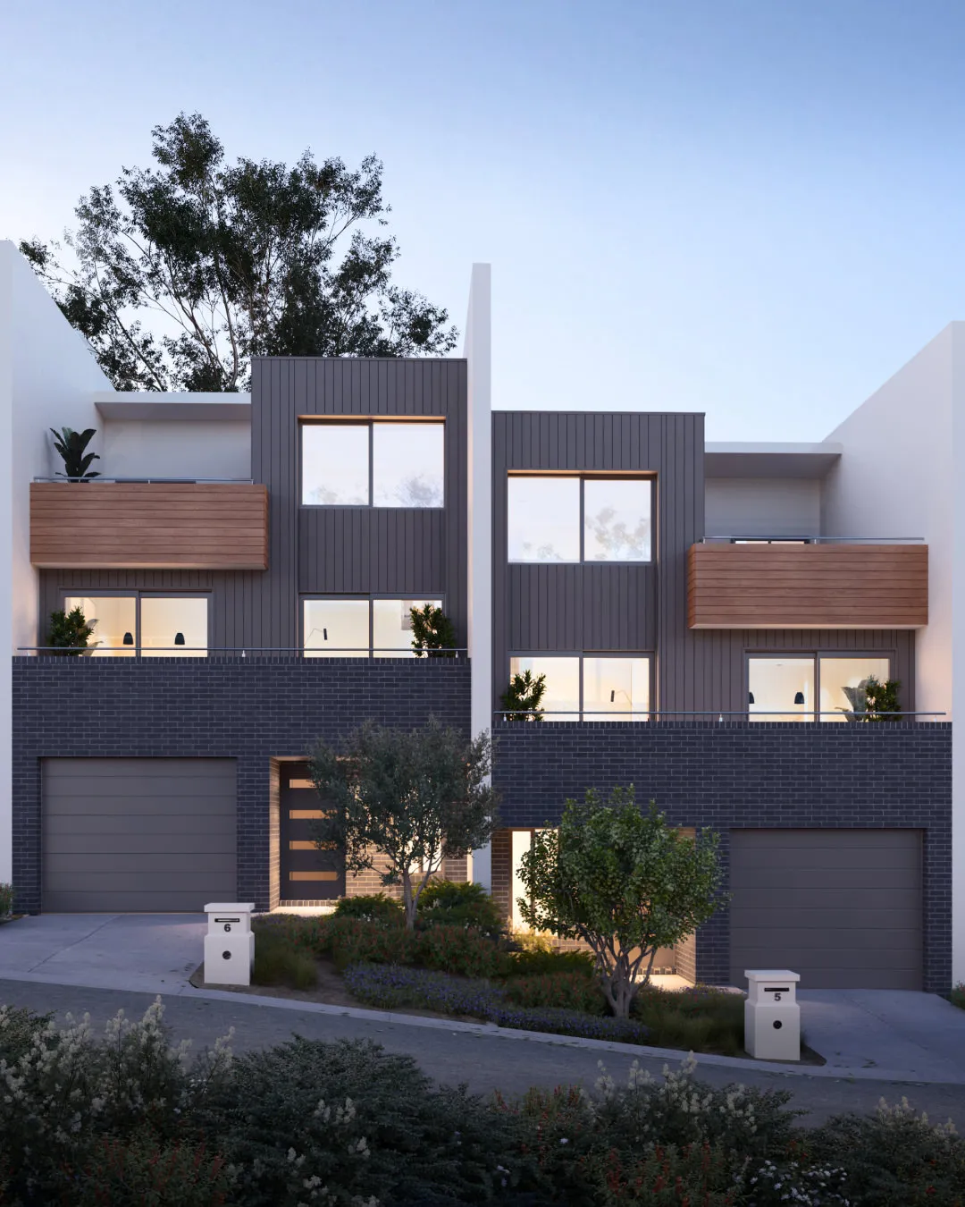 Modern duplex with dark brick garage bases, wood balconies, and large upper windows at dusk.
