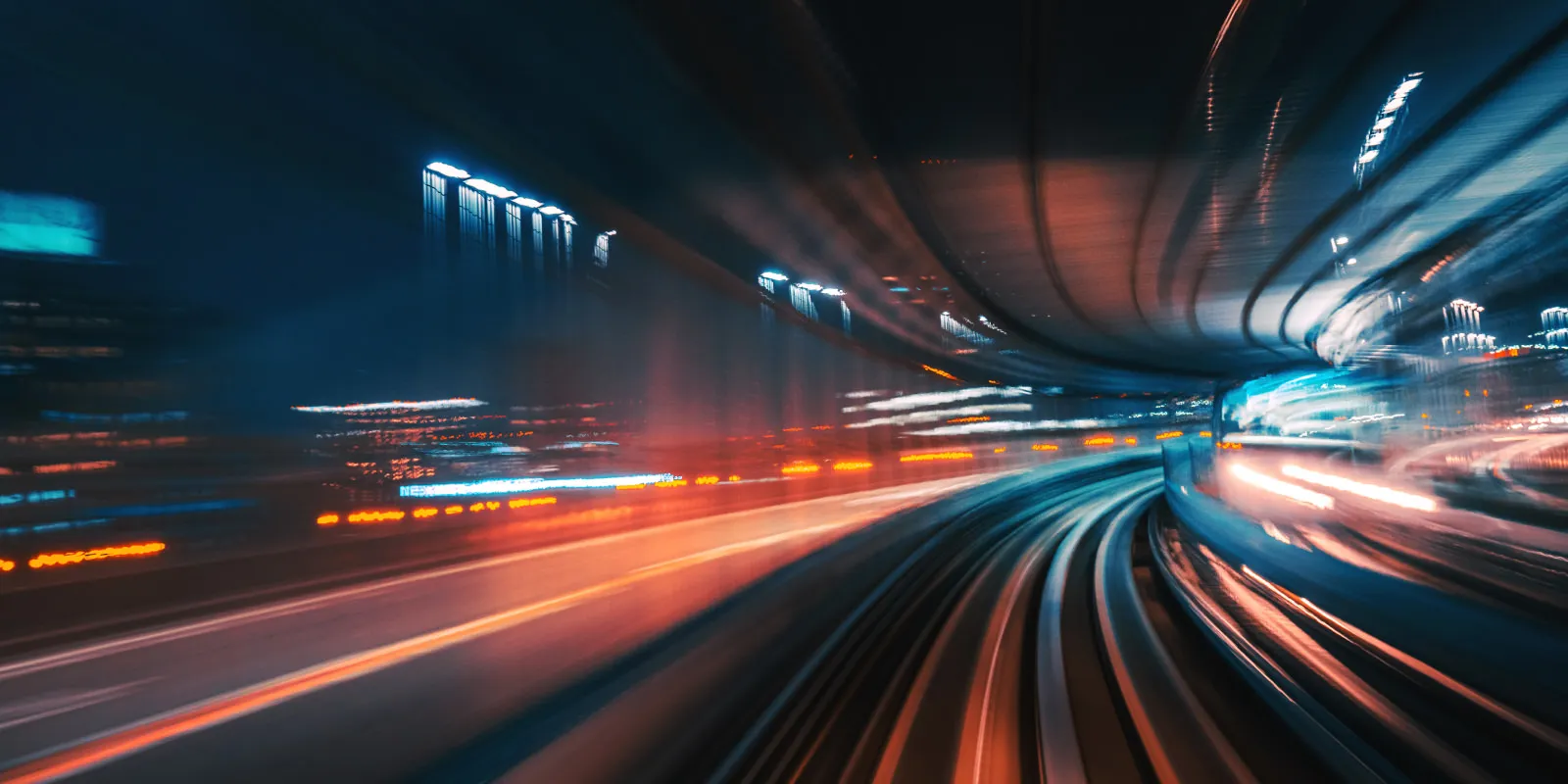 Blurred lights and rails in a tunnel, creating a futuristic, fast-moving effect at night.