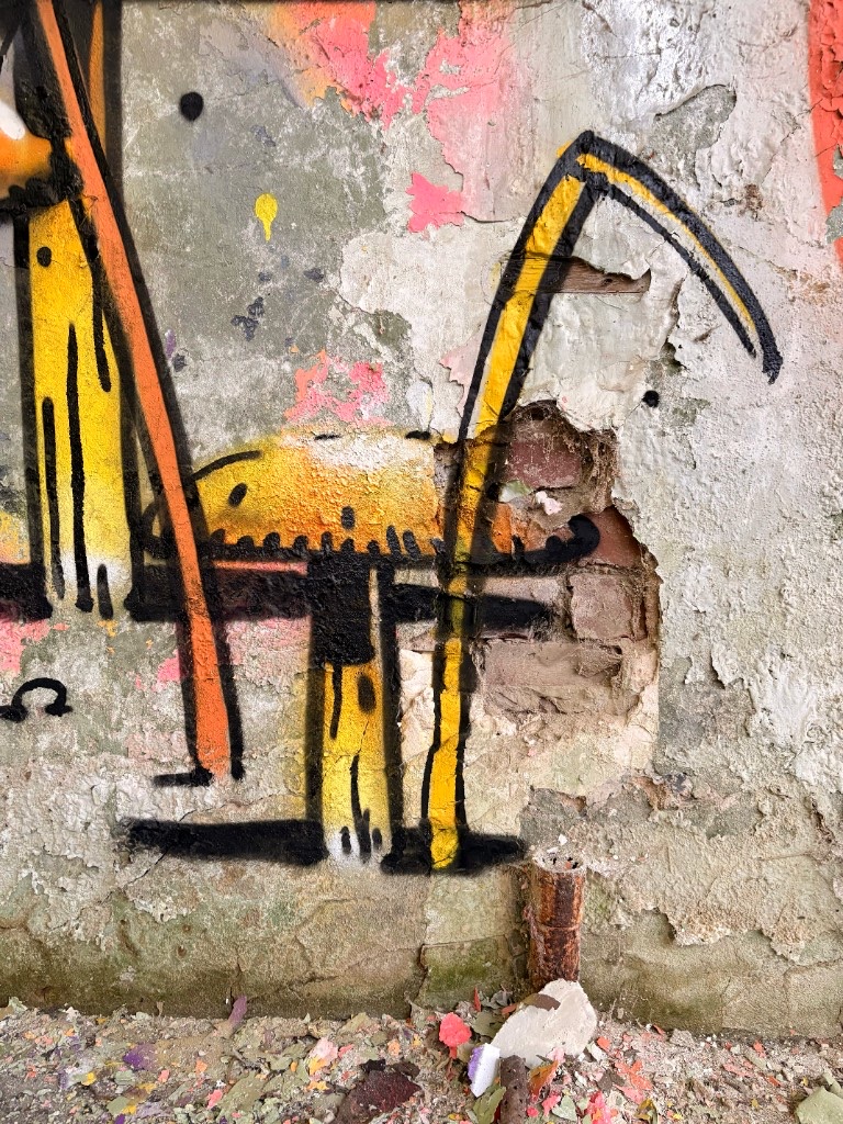 Close-up of a yellow fruiting body painted on peeling plaster in a derelict space