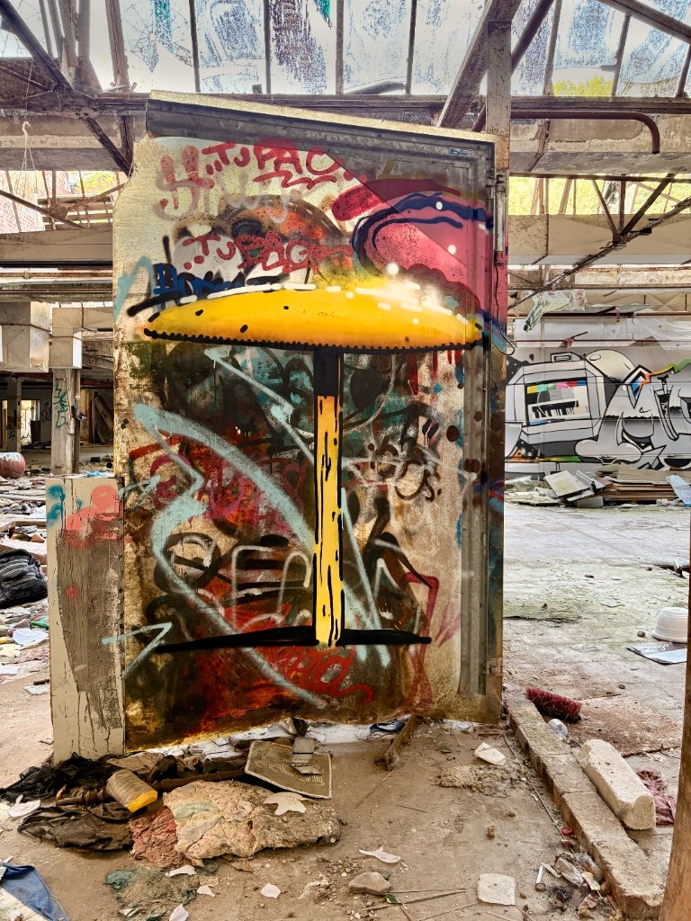 Large yellow fruiting body painted over layered graffiti on a freestanding panel