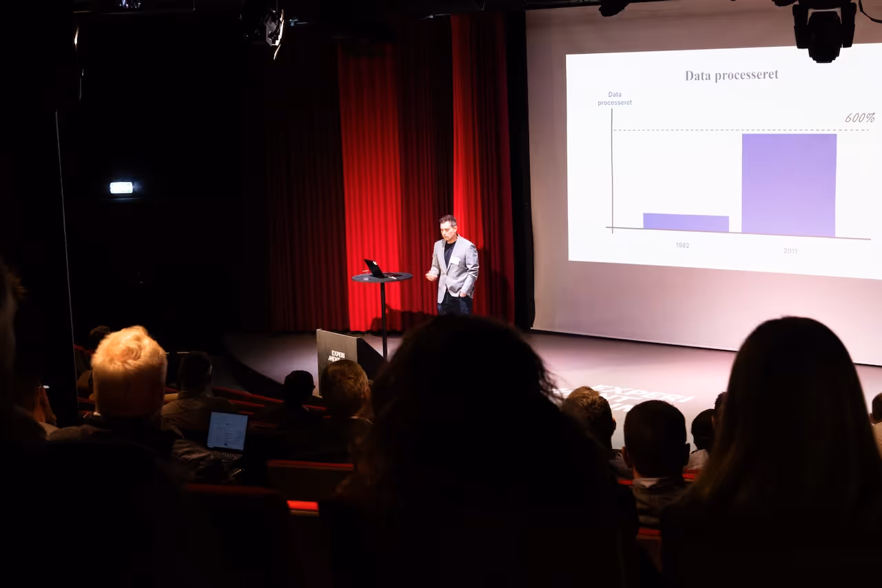 A man on stage talking in front of a crowd