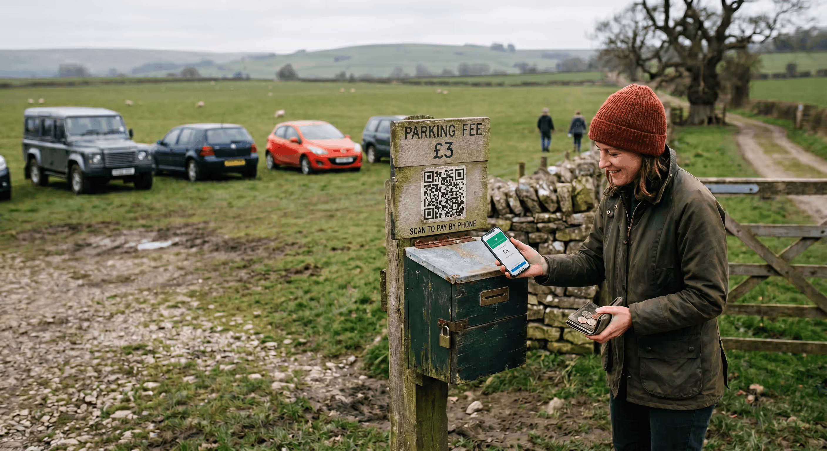 Woman paying a £3 parking fee by phone at a rural gravel parking area with cars and green fields in the background.