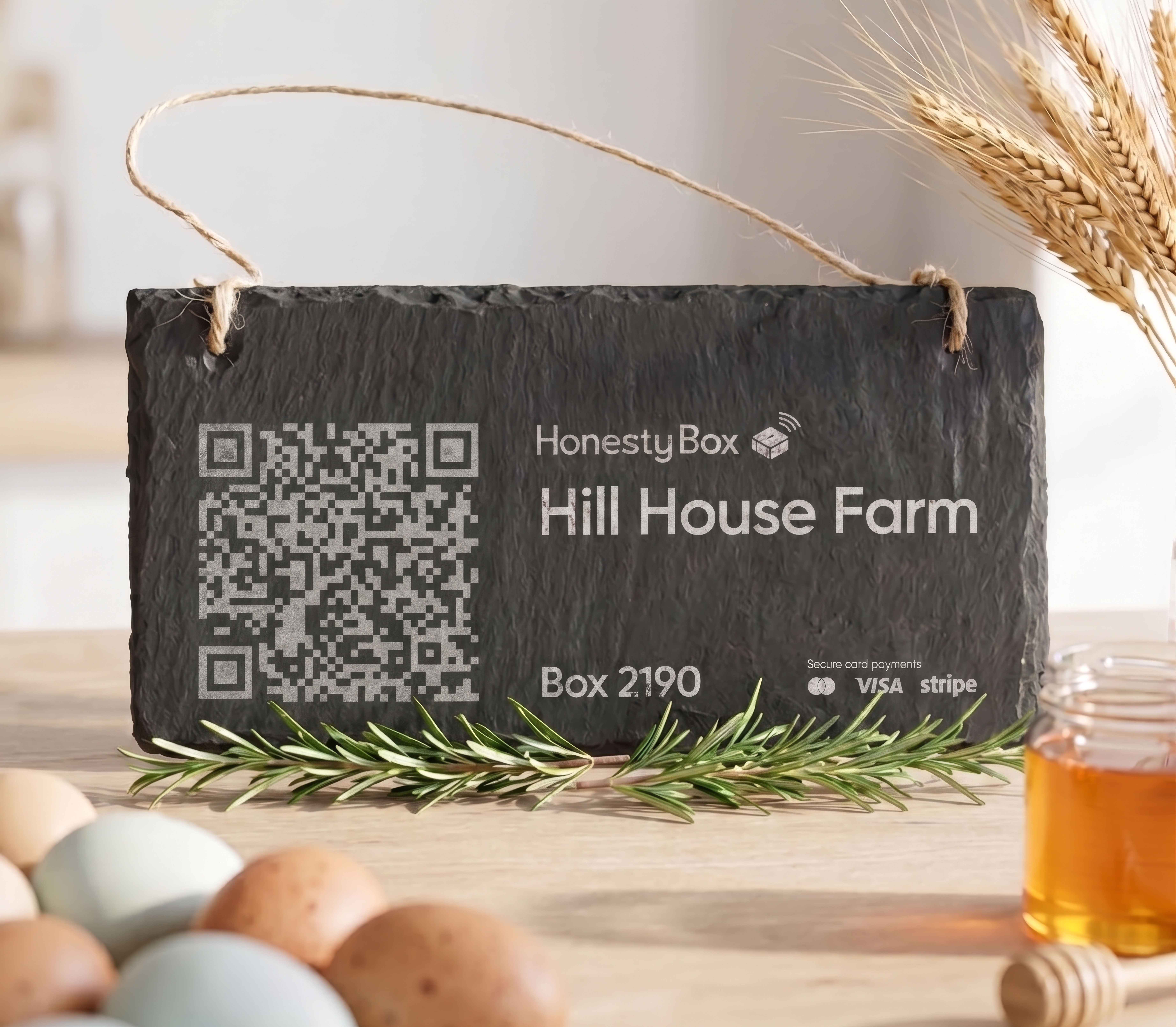 Black slate sign with QR code for Hill House Farm, box 2190, on a table with eggs, honey, and wheat.