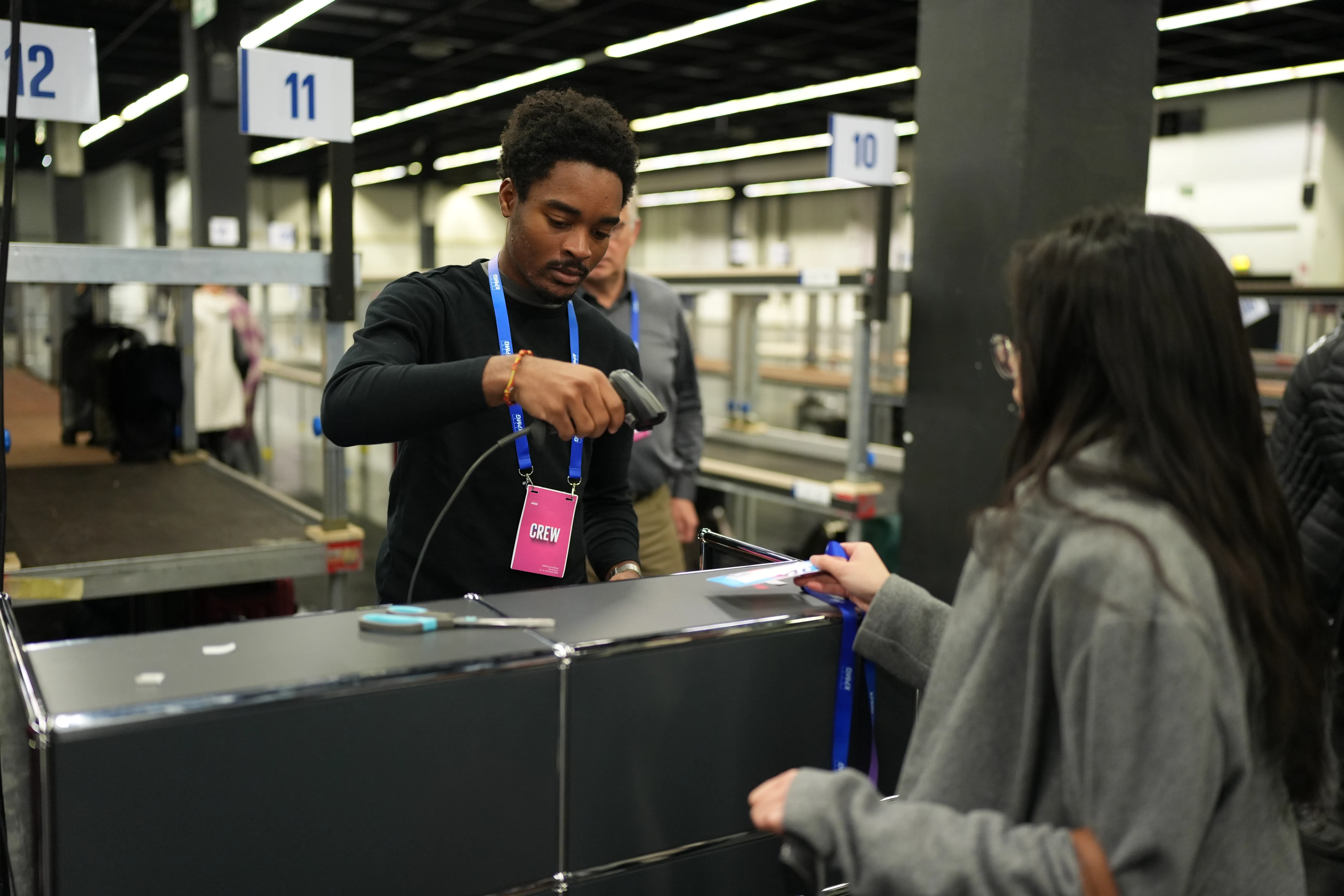 Einlasskraft mit Crew-Badge scannt am Halleneingang das Ticket einer Messebesucherin