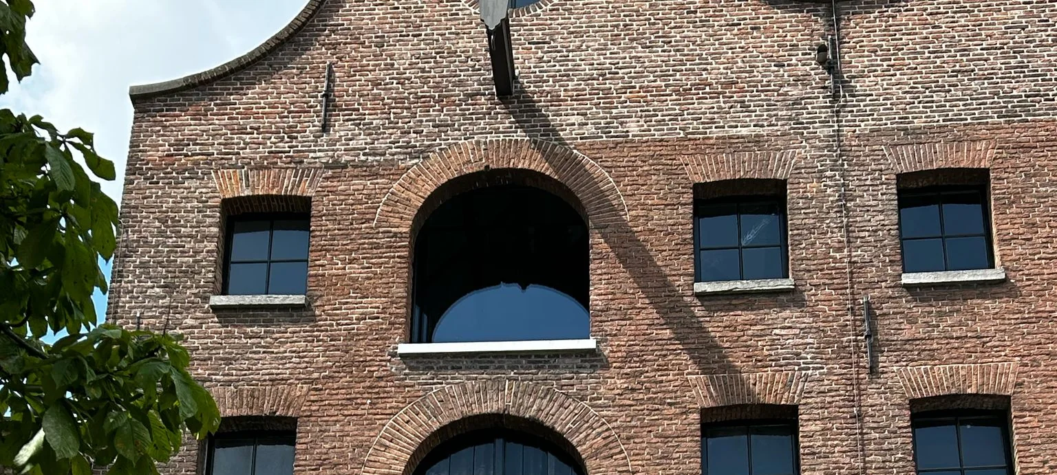 Monumentale voorgevel van De Dubbelde Palmboom met geopende luiken en glazen etalages.