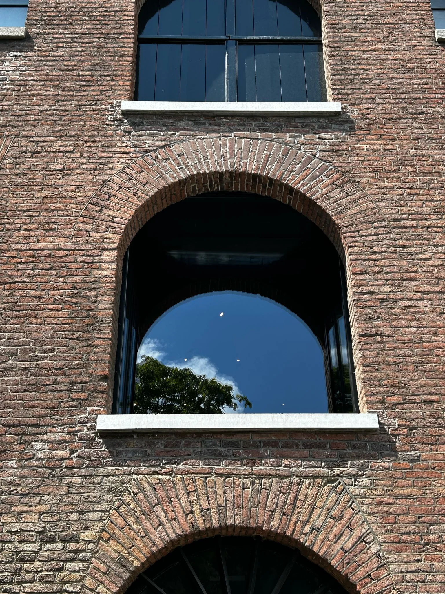 Detail van een geopende luikopening met de glazen etalage in de bakstenen gevel.