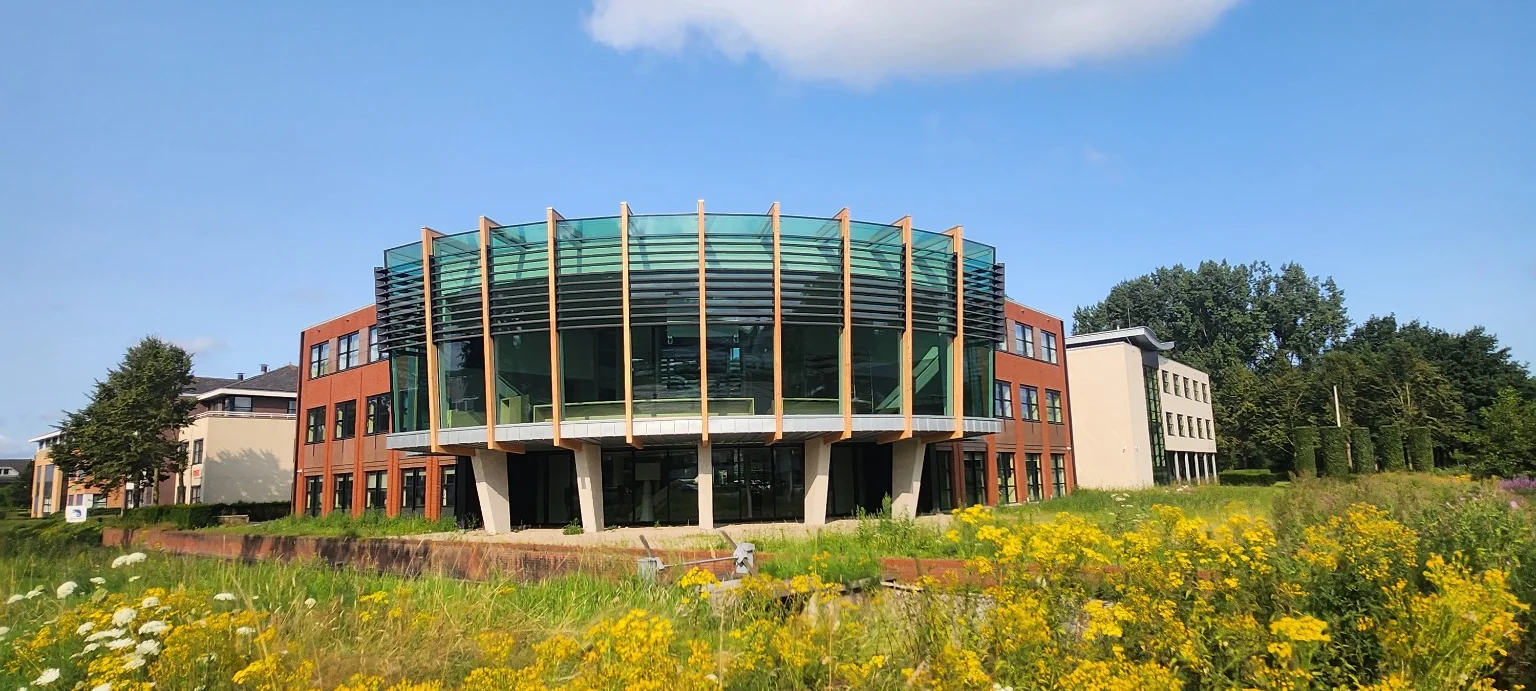 Transparante uitbreiding van het gemeentehuis in Nijkerk met glazen raadzaal en houten gevelstijlen.