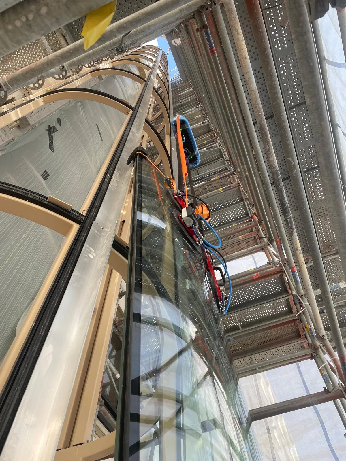Gebogen glas wordt gecontroleerd tussen steiger en liftschacht geleid.