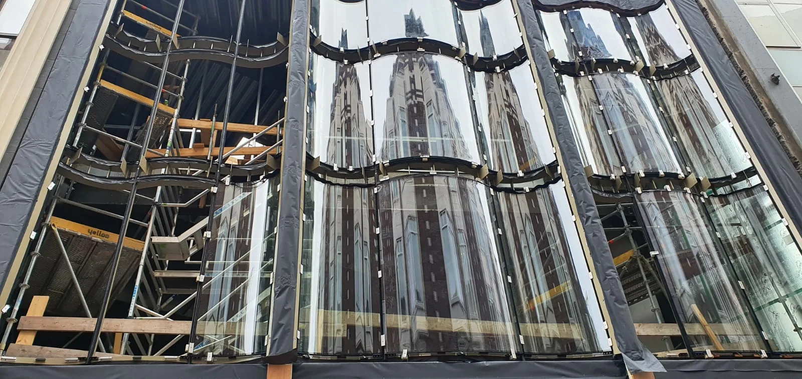 Vormvolgende staalconstructie achter gebogen glas.