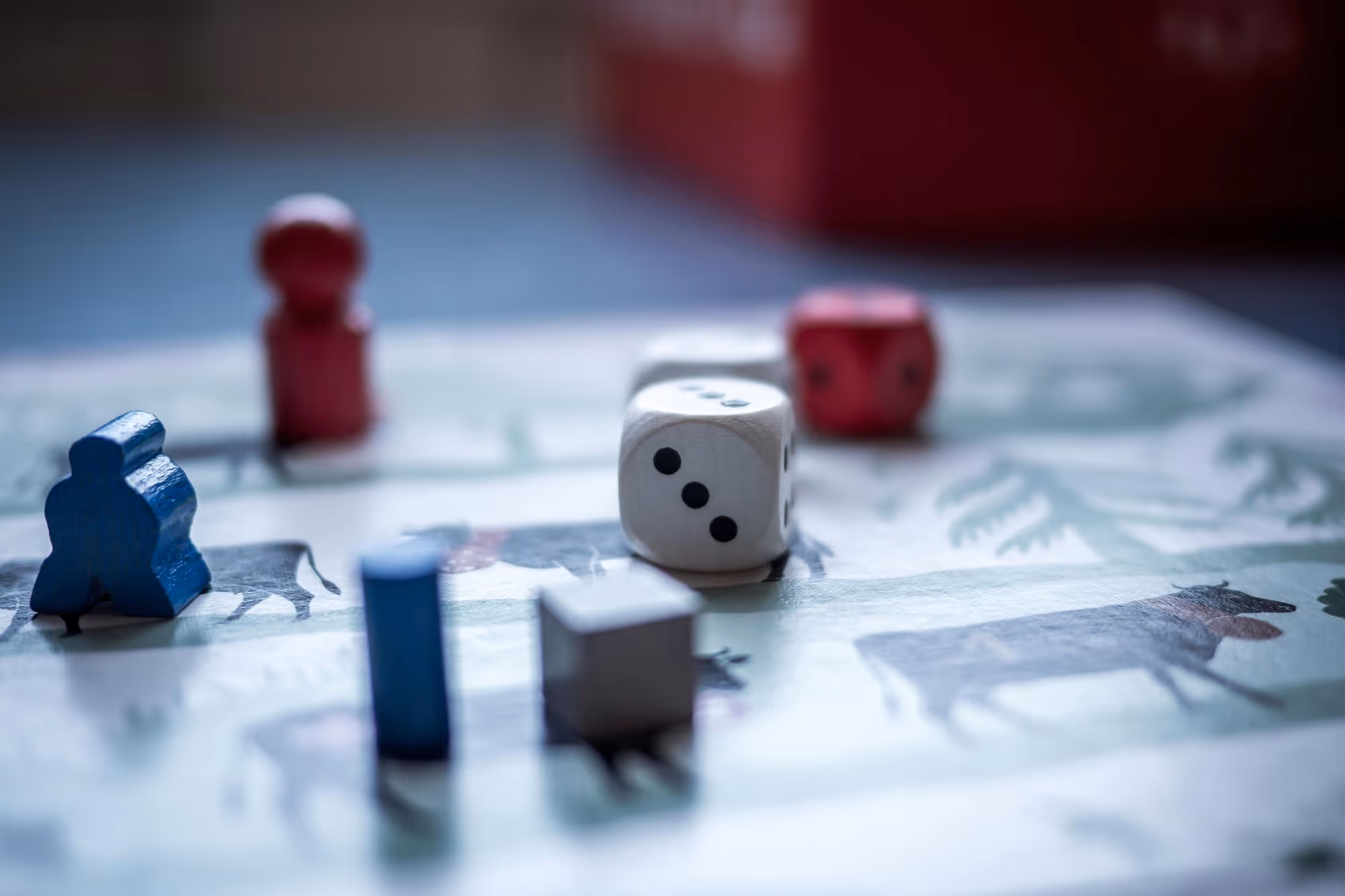 Close-up of board game pieces, including dice and colored player tokens on a game board with animal images.