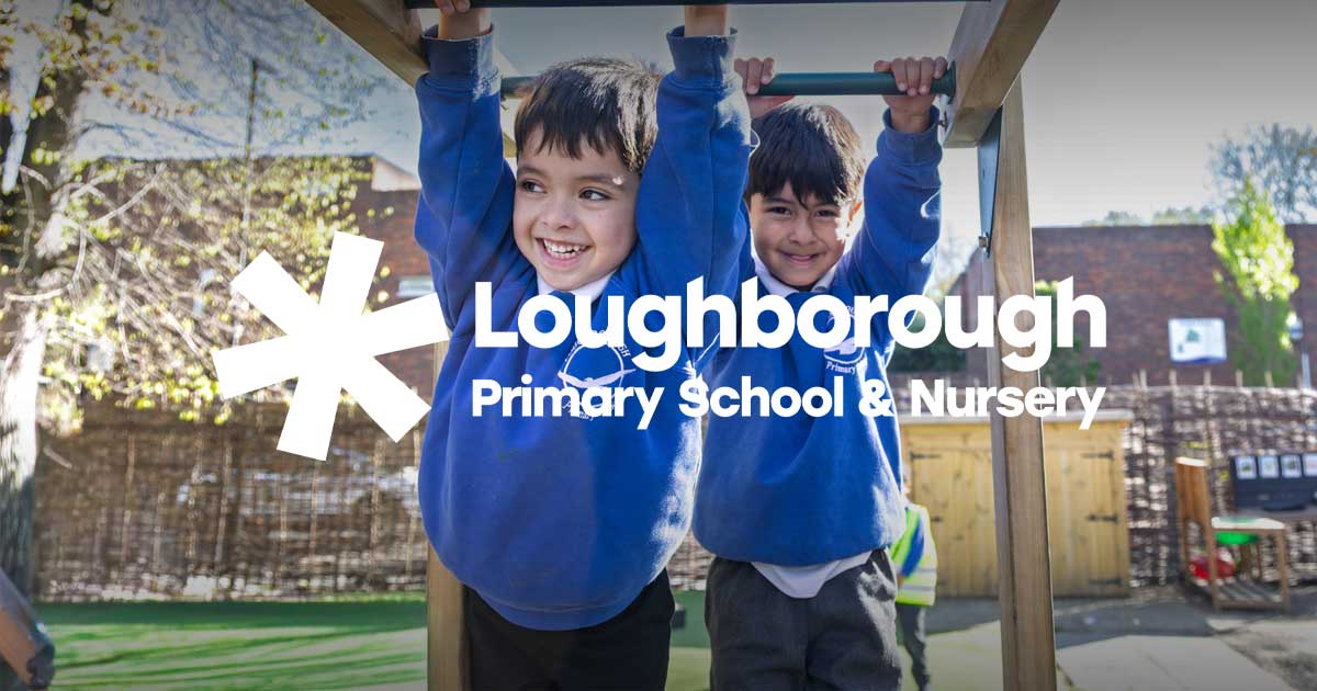 Two boys in blue hoodies smiling and hanging from playground monkey bars outdoors.