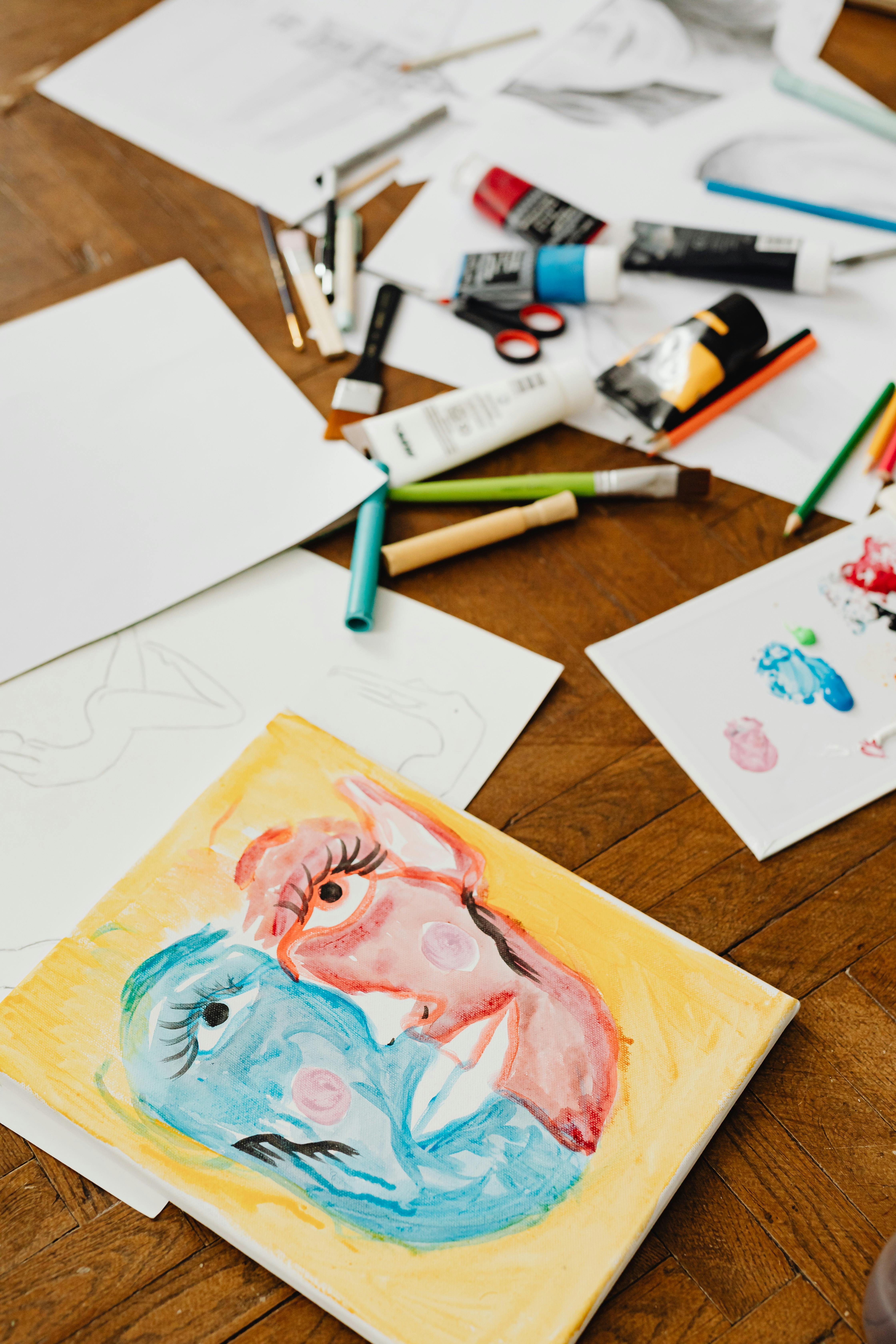 Canvas painting of two abstract faces in blue and red with long eyelashes on a wooden floor.