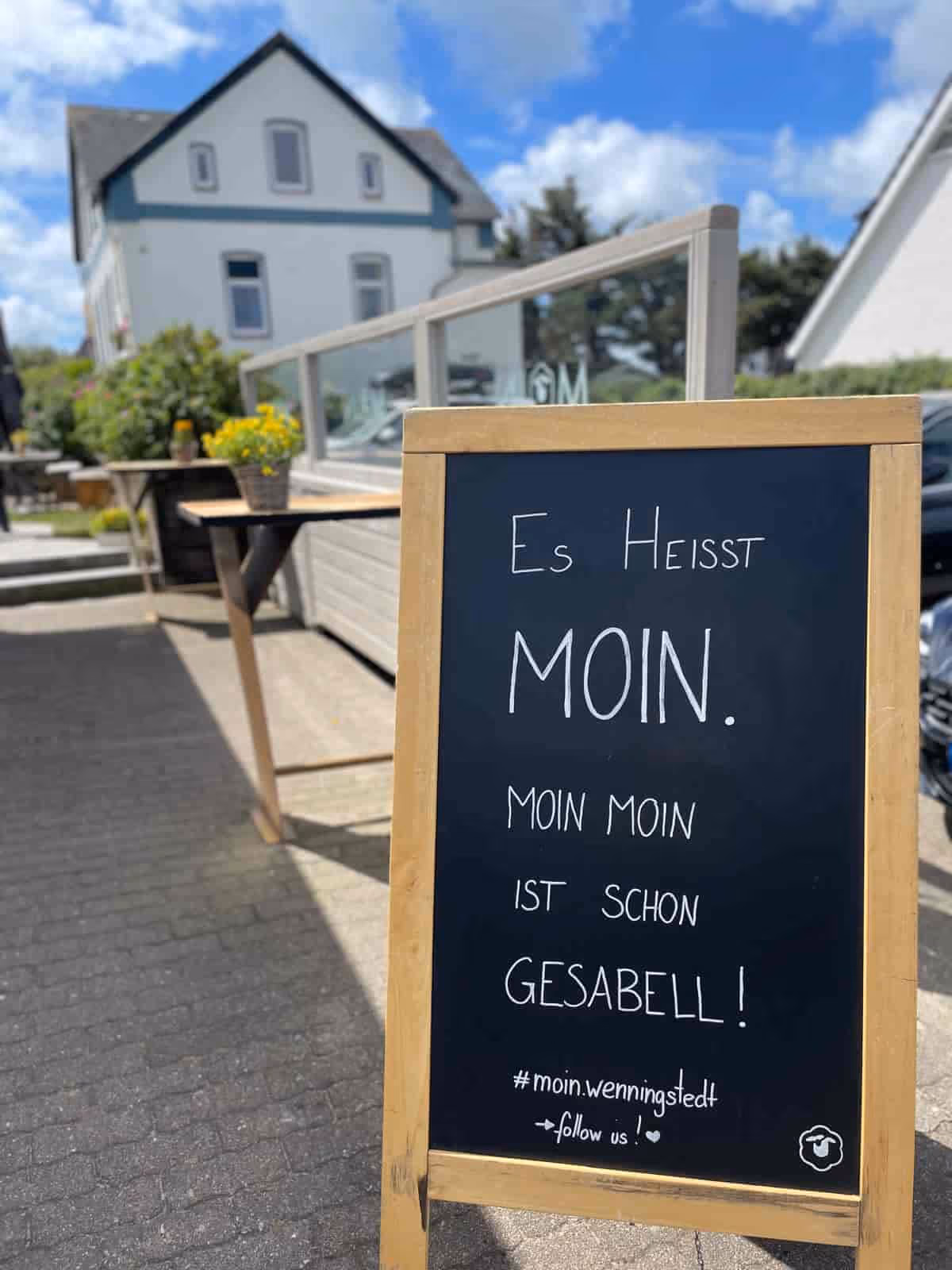Tafel vor einem Haus mit dem Spruch: Es heißt Moin. Moin Moin ist schon gesabell!
