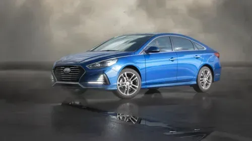 Blue Hyundai Sonata sedan parked on wet reflective surface under cloudy sky.